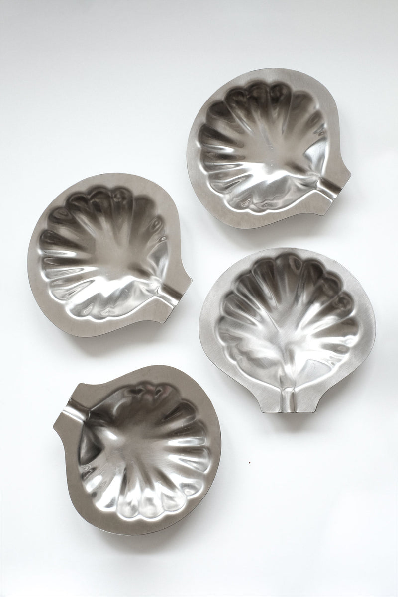 Set of four polished metal shell-shaped decorative dishes