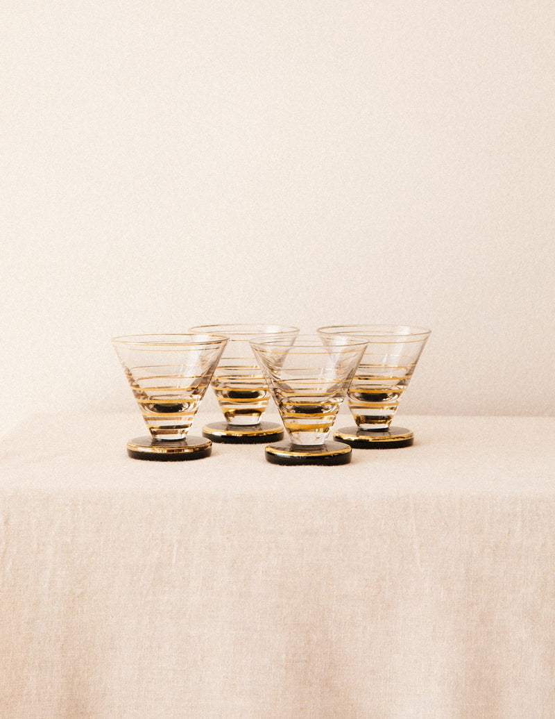 Four amber-tinted cordial glasses with ridged bases on beige surface