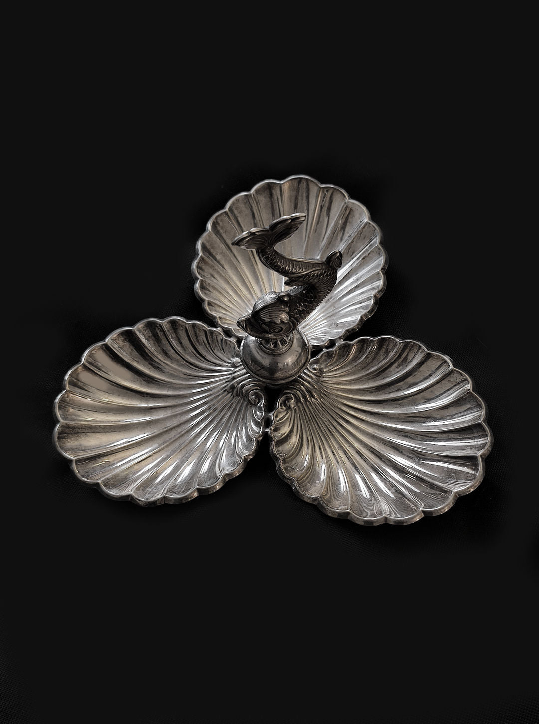 The Les Objoies Shell & Fish Triple Tray, featuring silver-plated shell-shaped compartments and a central fish figurine, stands elegantly against a dark background.