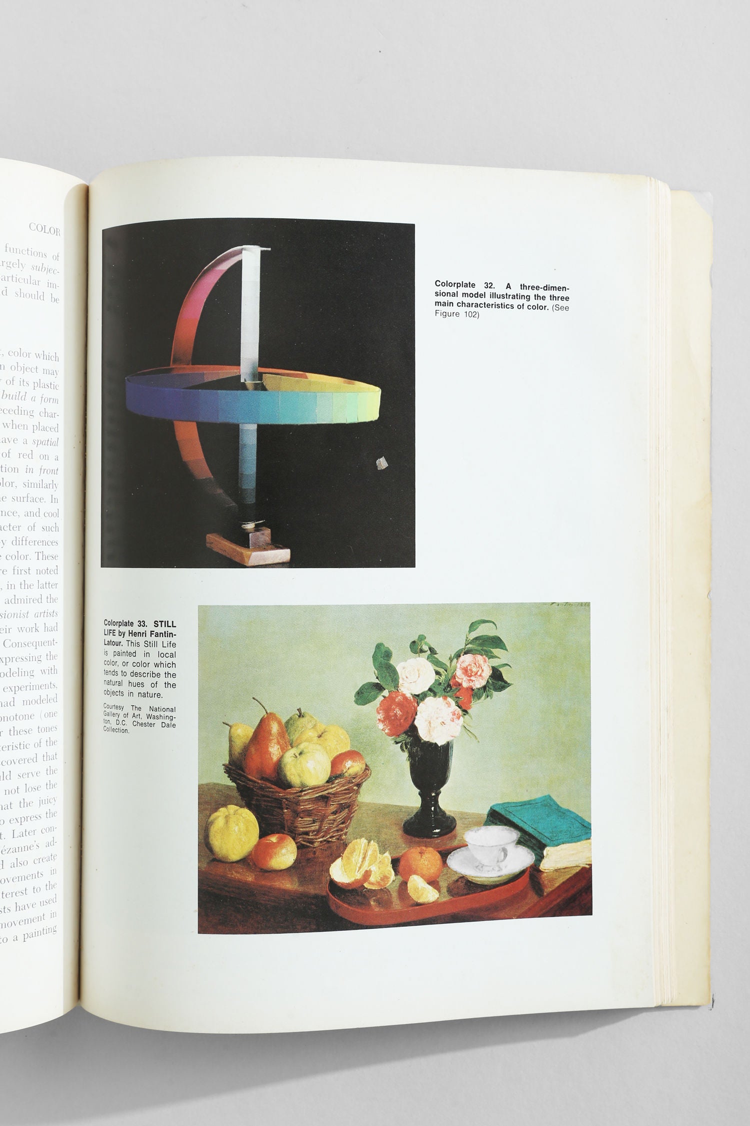 The Villa 'Art Fundamentals' Book is open, showing a geometric sculpture with colorful bands on one page and a classic still life of fruit, basket, teacup, and flowers on the other.