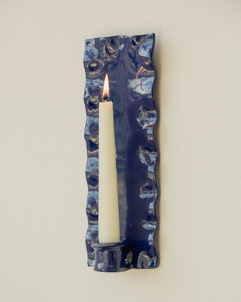 Blue ceramic rectangle candle sconce with lit taper candle