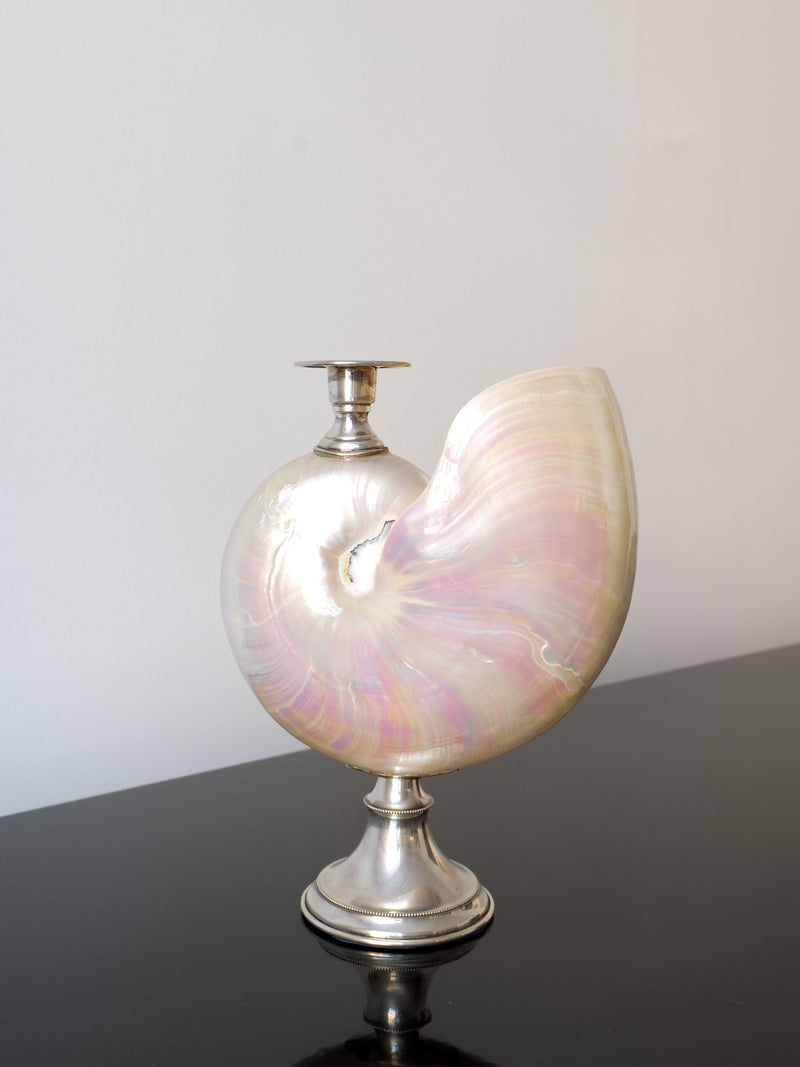 A decorative piece from Collection apart, the Nautilus Silver Candle Holder features a pearlescent nautilus shell mounted on an Italian silver stand and is displayed on a glossy black surface.