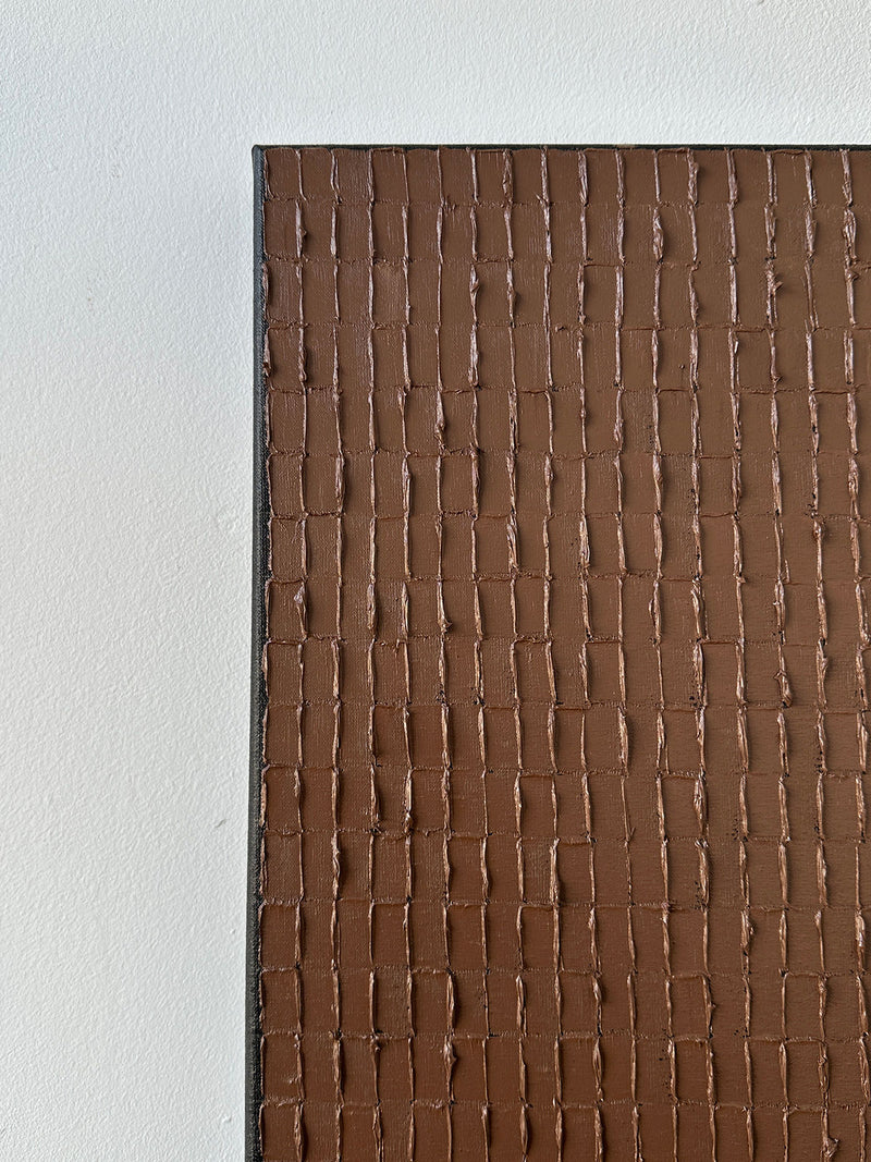 Close-up of 'Light Umber'—an oil on canvas by Roi Elmaliah—featuring a brown, grid-textured surface on the right and a smooth white background on the left.