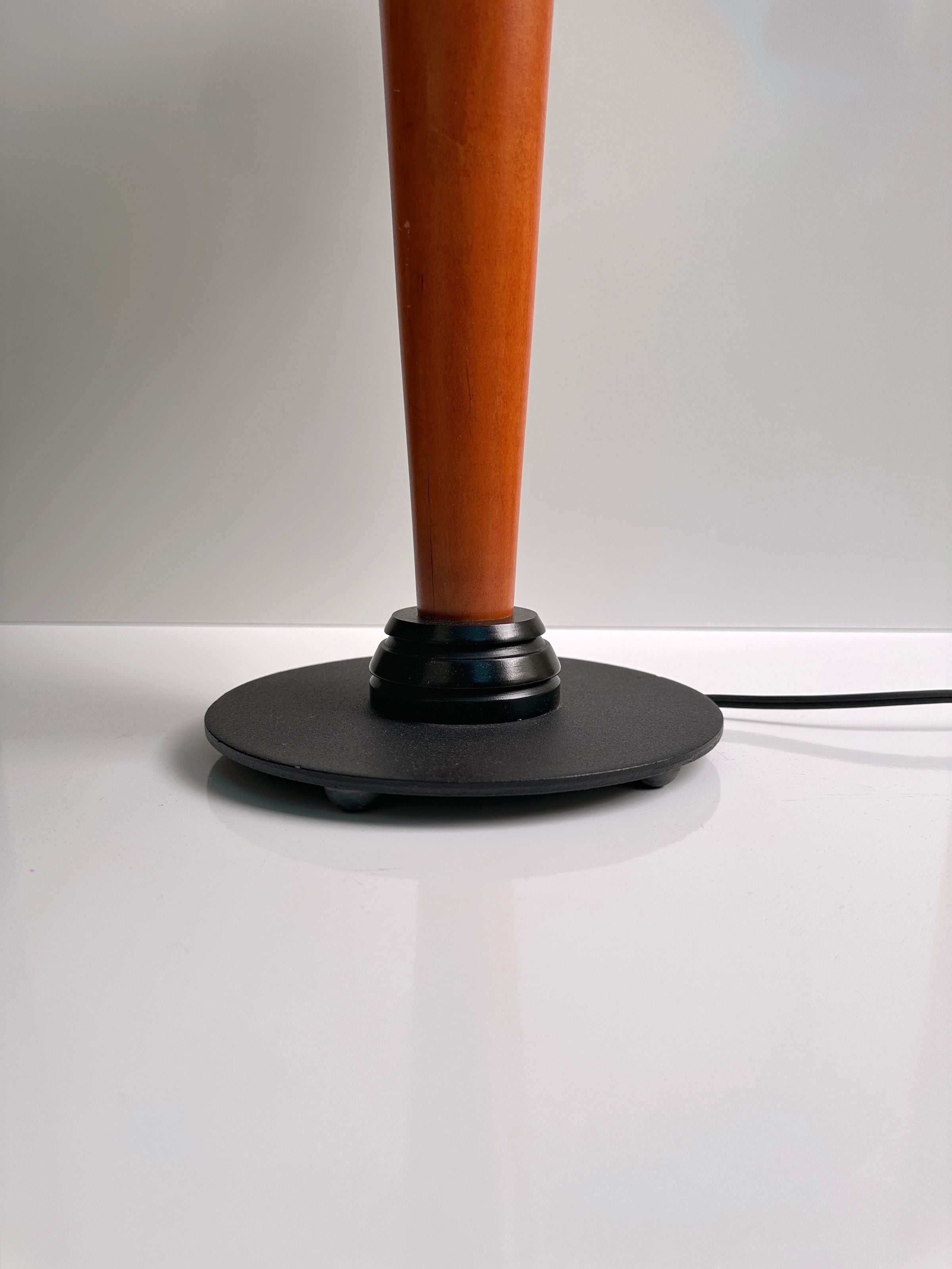 Close-up view of the Dodo Vintage 1950s Scandinavian Banker Lamp, featuring a wooden stand with a circular black base that echoes Mid-Century design. It sits elegantly on a white surface, with a thin electric cord extending from the base. A plain light grey background effortlessly highlights its sleek, minimalist style.