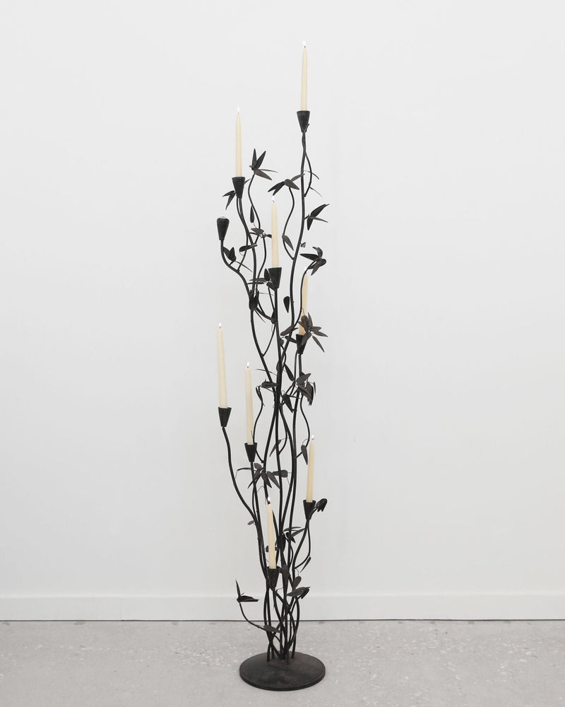 Tall black iron candelabra sculpture with branching stems and leaves
