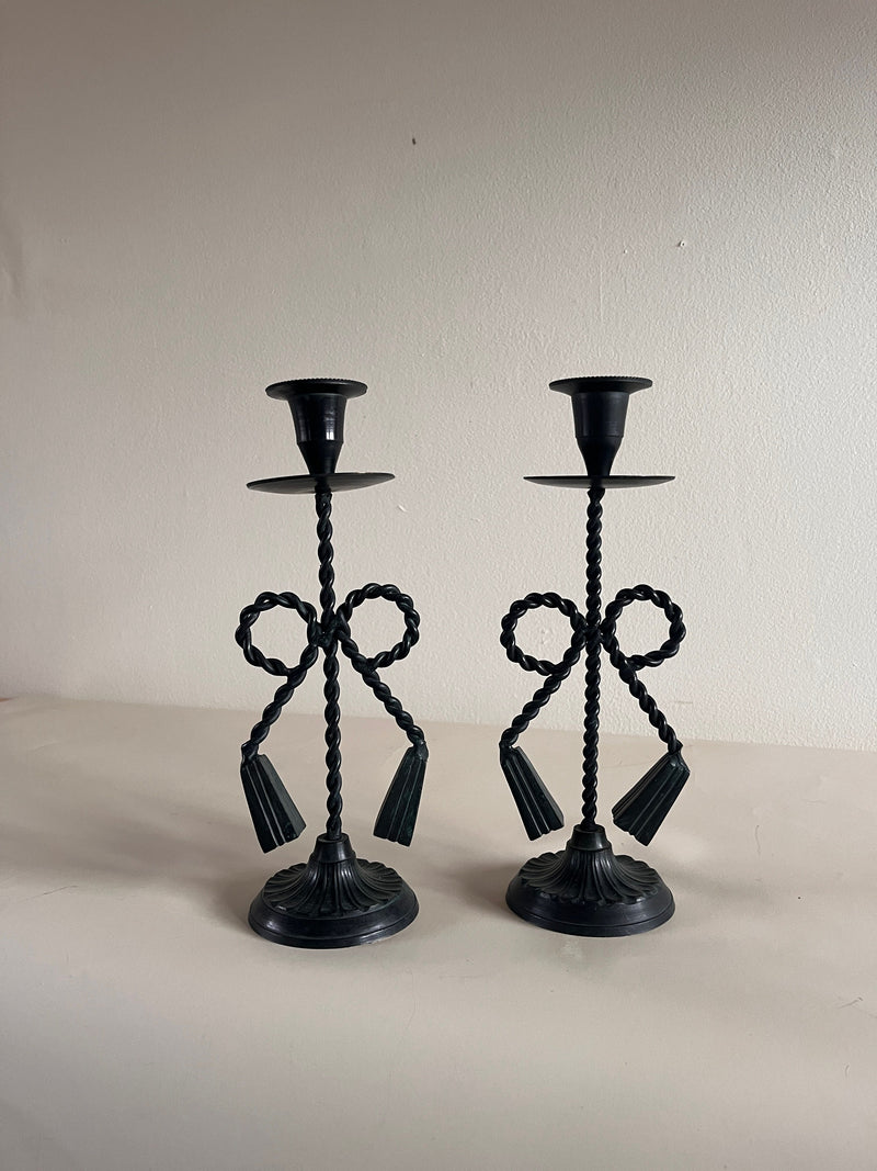 The Vintage Bow and Tassle Candleholders by Maud Vaughan feature an ornate twisted rope design with intricate bow and tassel details on the stem, elegantly standing against a neutral background.