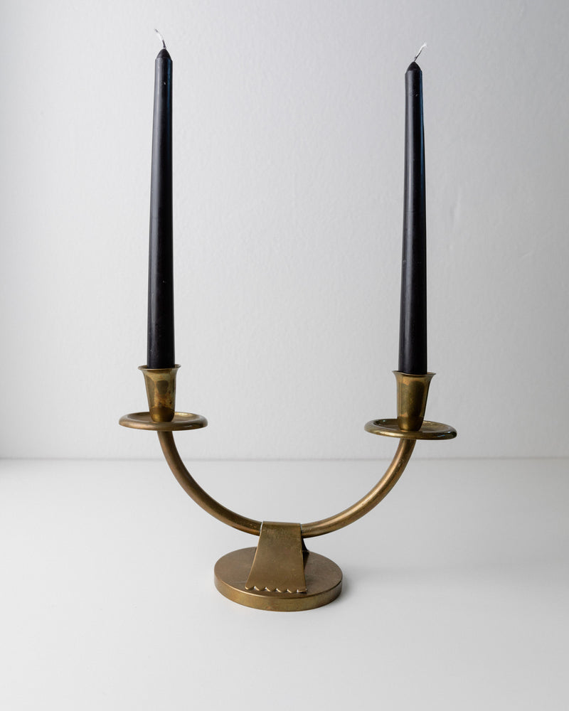 The Art Deco Candleholder by Bottega Jacobs, crafted in Italy in the 1960s, features a minimalist design with two unlit black candles on a white surface. Its curved lines and round base exude timeless elegance against a plain backdrop.