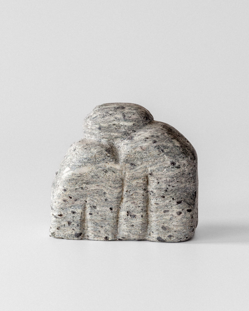 Abstract sculptural stone form with curved organic shapes in speckled gray granite