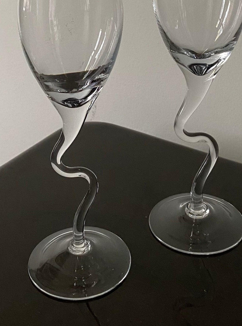 Two empty Set of Vintage 80s Champagne Glasses with twisted stems by Les Objets Amsterdam standing on a shiny black surface.