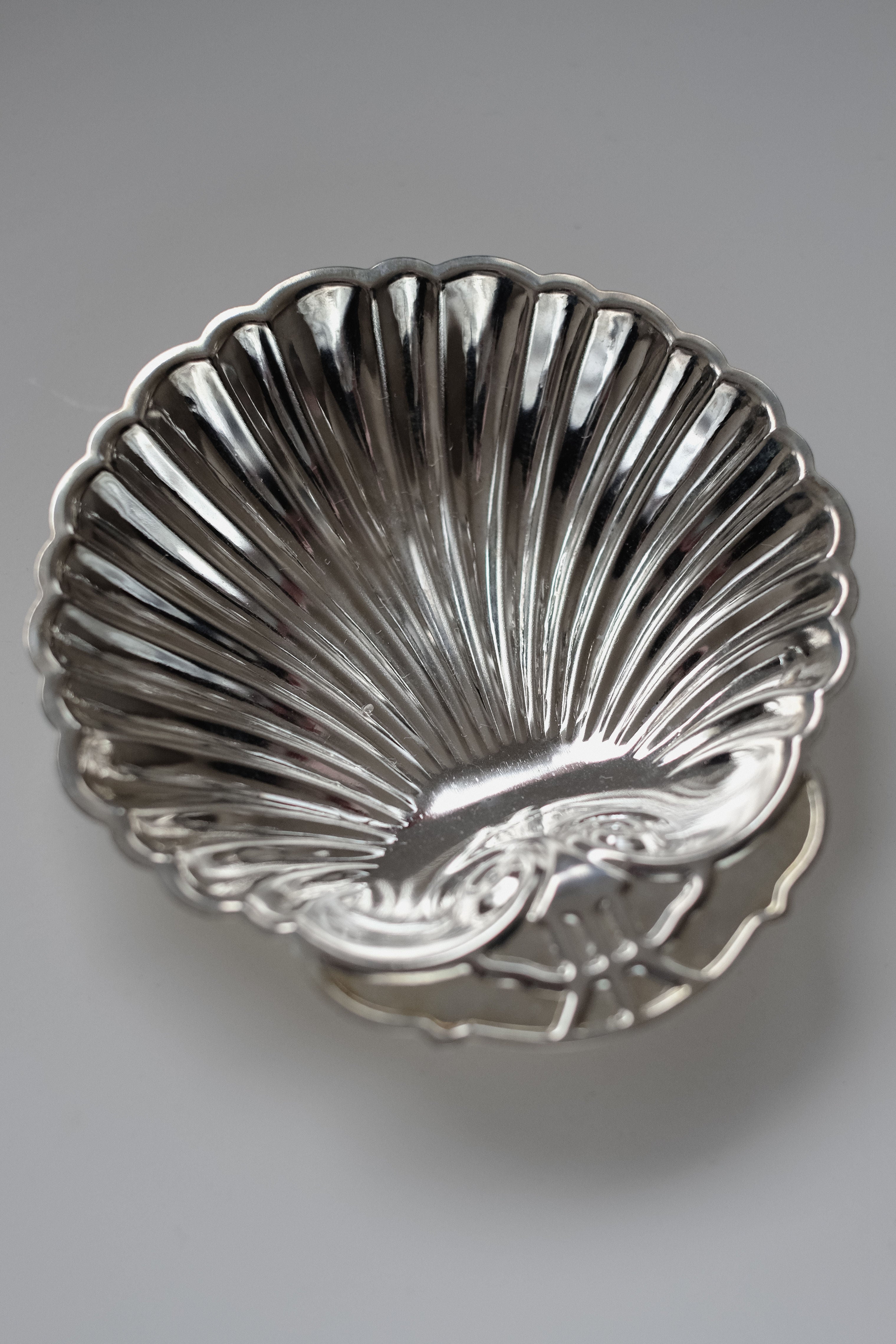 A Set of 2 Silver-plated Shell Trays by septembre studios, featuring ornate ridges and intricate details, enhances any dining setting with timeless elegance against a light gray background.