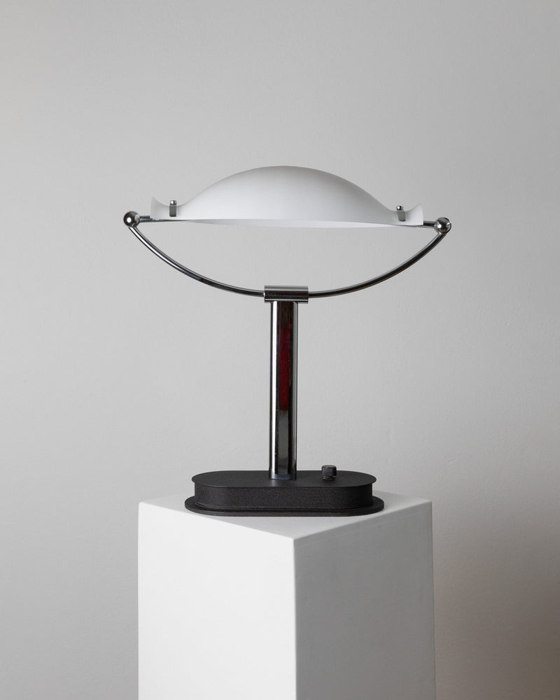 The Murano Glass Table Lamp by Bottega Jacobs, an Italian 1970s piece, showcases a space age design with a white dome-shaped shade and sleek chrome stand on a black base, elegantly displayed on a white pedestal against a neutral background.