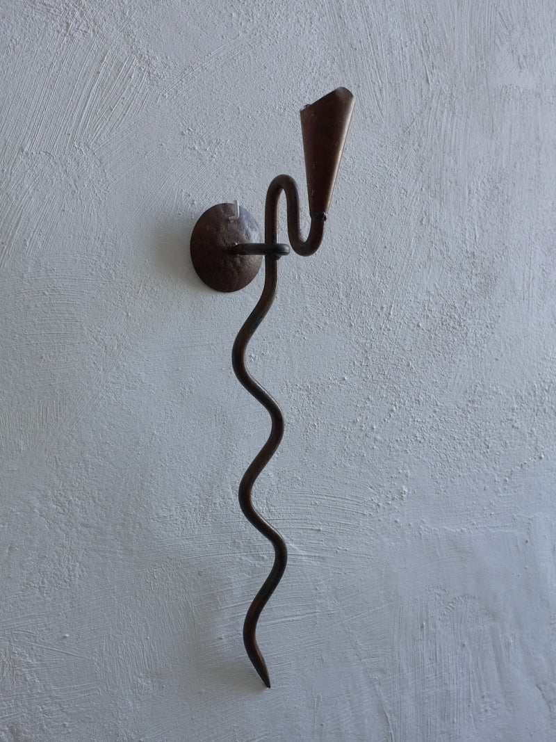 Wrought iron candle holder with serpentine stem wall-mounted detail