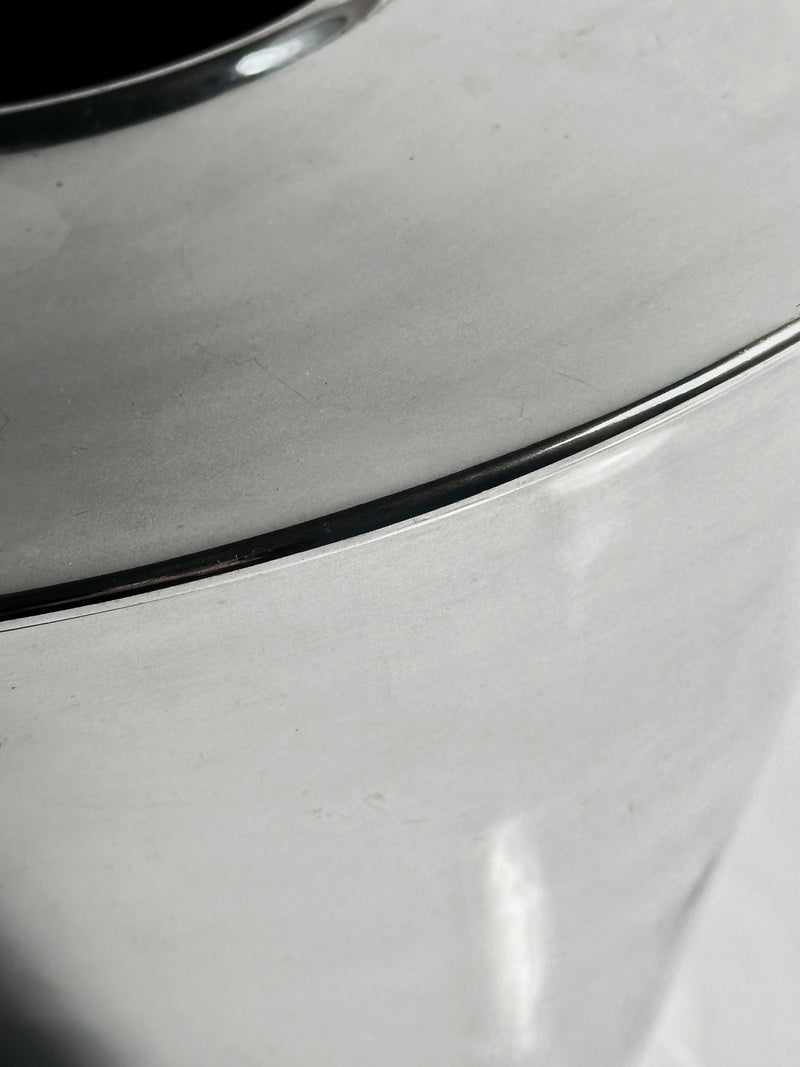 Close-up view of Dodo Vintage's Fink Germany heavy silver-plated vase, reminiscent of a 1980s jewelry design, with smooth curves and a reflective finish that highlight its shiny metallic surface and subtle play of light.