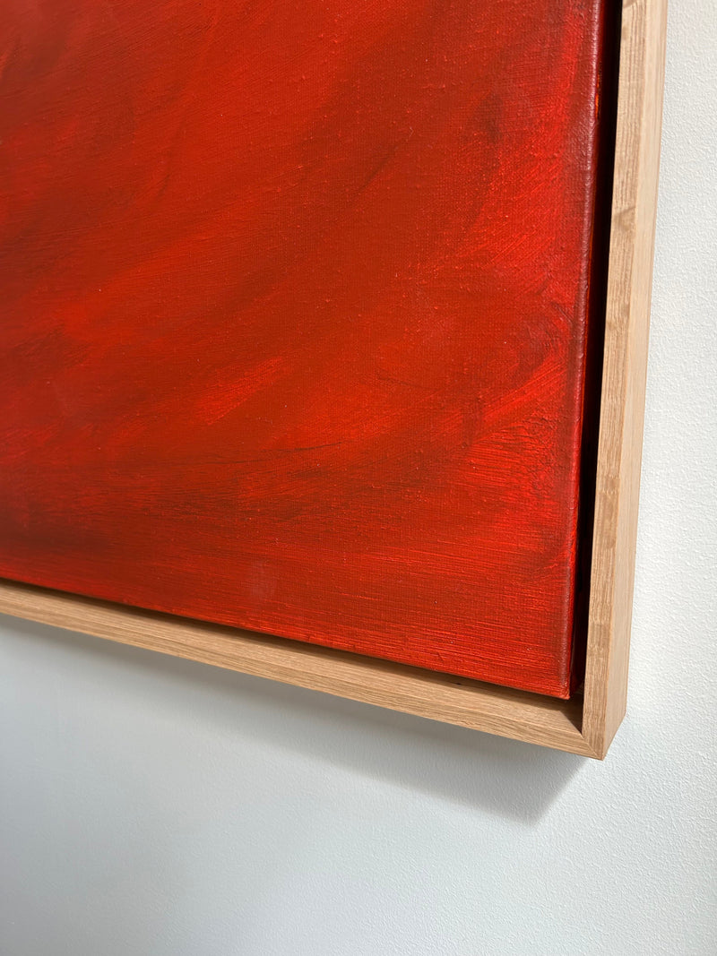 A close-up of an abstract diptych from Mattias Storm's Terra Incognita (Diptych) - Mixed media on canvas series features vibrant red and orange hues, framed in light wood. The mixed media painting has a textured surface with various shades blending together. The wall behind the artwork is white.
