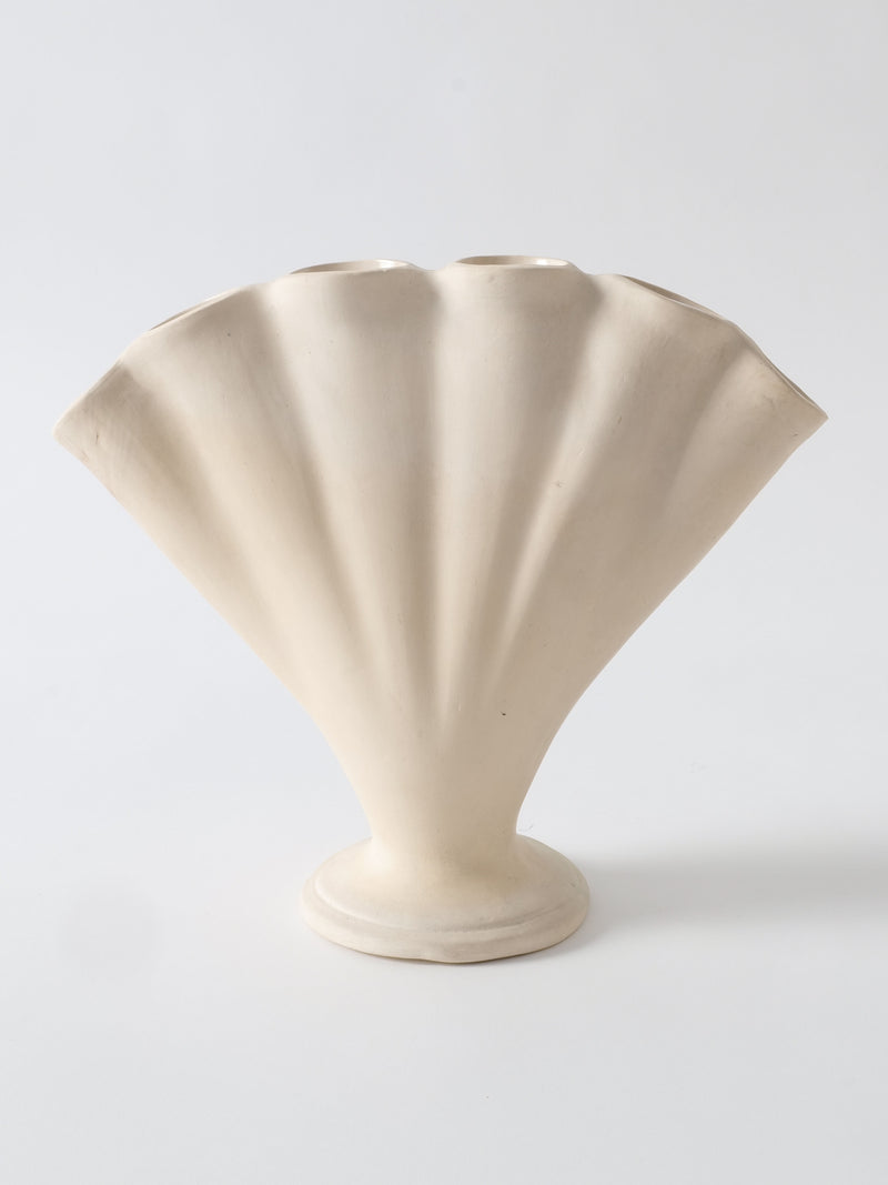 A photo of the Tulipiere Vase 1930s designed in the shape of a fan. The vase, from Collection apart, is beige and features a fluted, scallop-like pattern with a rounded base, accentuating its fan-like appearance. The background is plain white.
