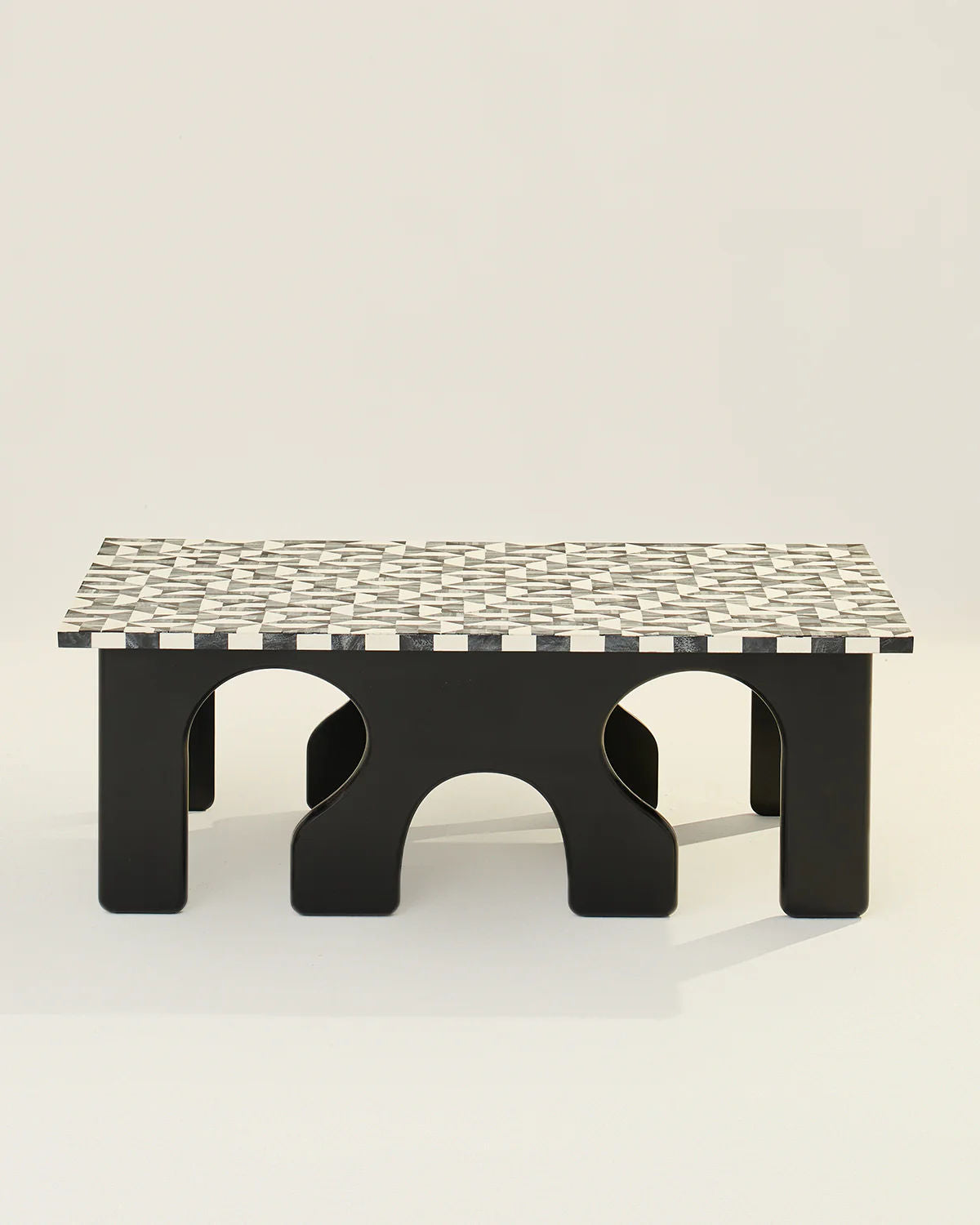 The Leo Coffee Table by LMNOH features a black and white checkerboard pattern with bone inlay on the tabletop and elegantly arched legs, all set against a plain background.