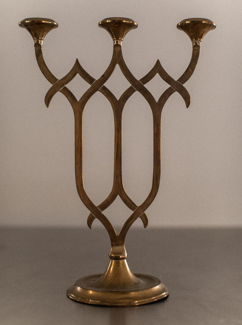 Brass candleholder with intricate filigree design and antique finish