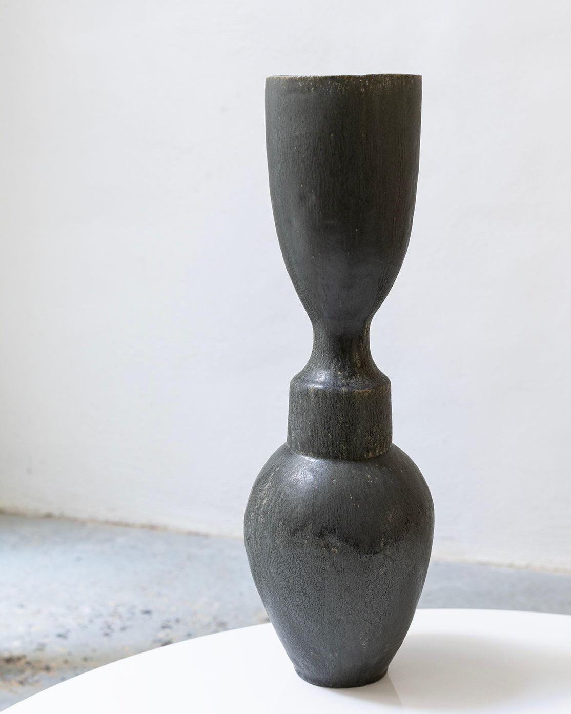 Black ceramic vase on a white surface with a light gray background