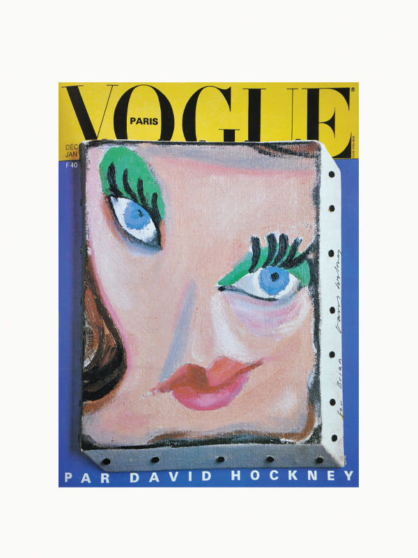 A Vogue Paris magazine cover features a stylized painted face by David Hockney, echoing the distinctive style found in Maison Plage's Hockney Posters by David Hockney. The close-up artwork showcases vibrant blue eyes, green eye makeup, and full red lips. A bright yellow background contrasts strikingly with the blue face, reminiscent of Hockney's famous posters.