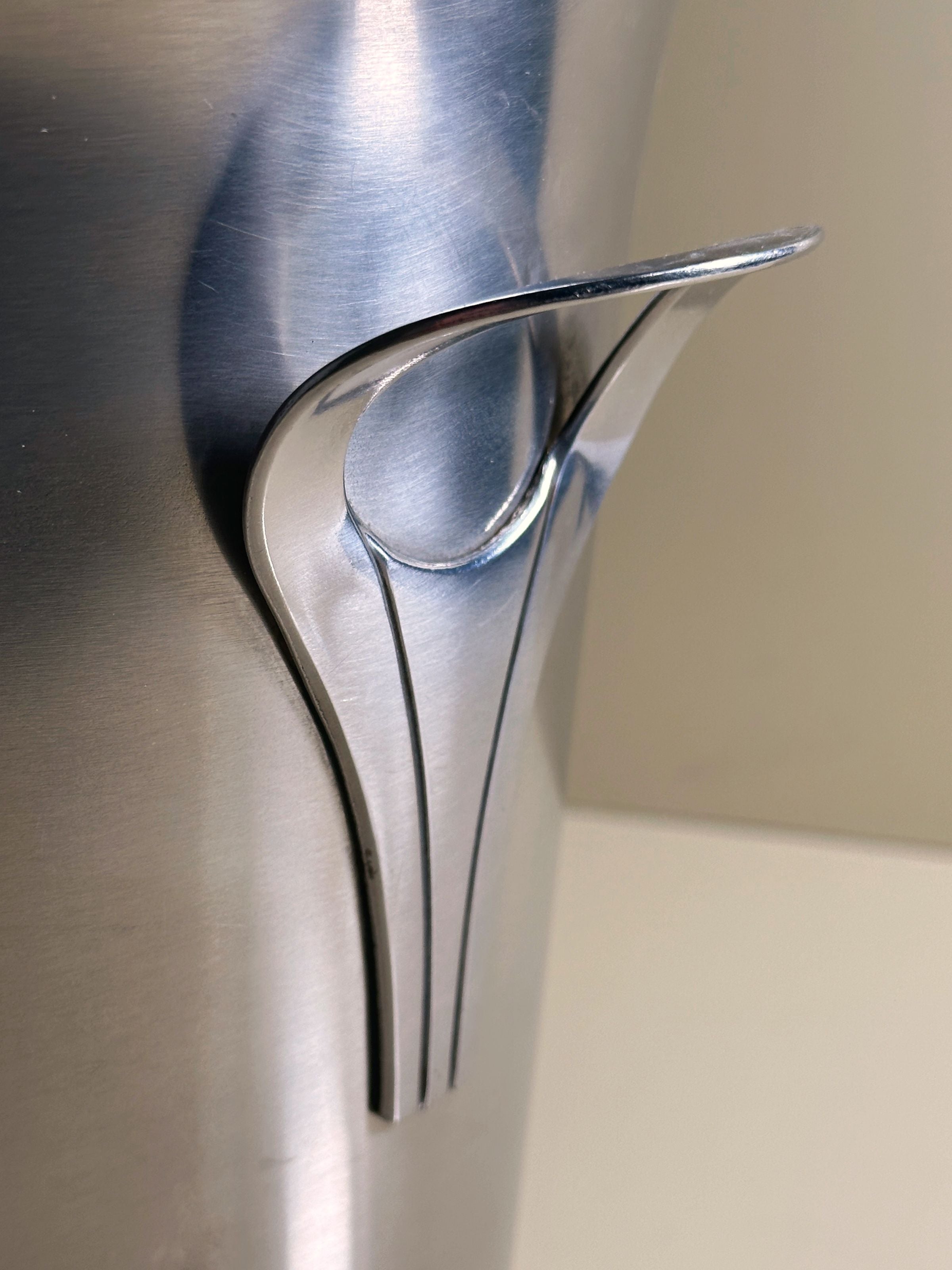 Close-up of elegant curved handle detail on stainless steel ice bucket