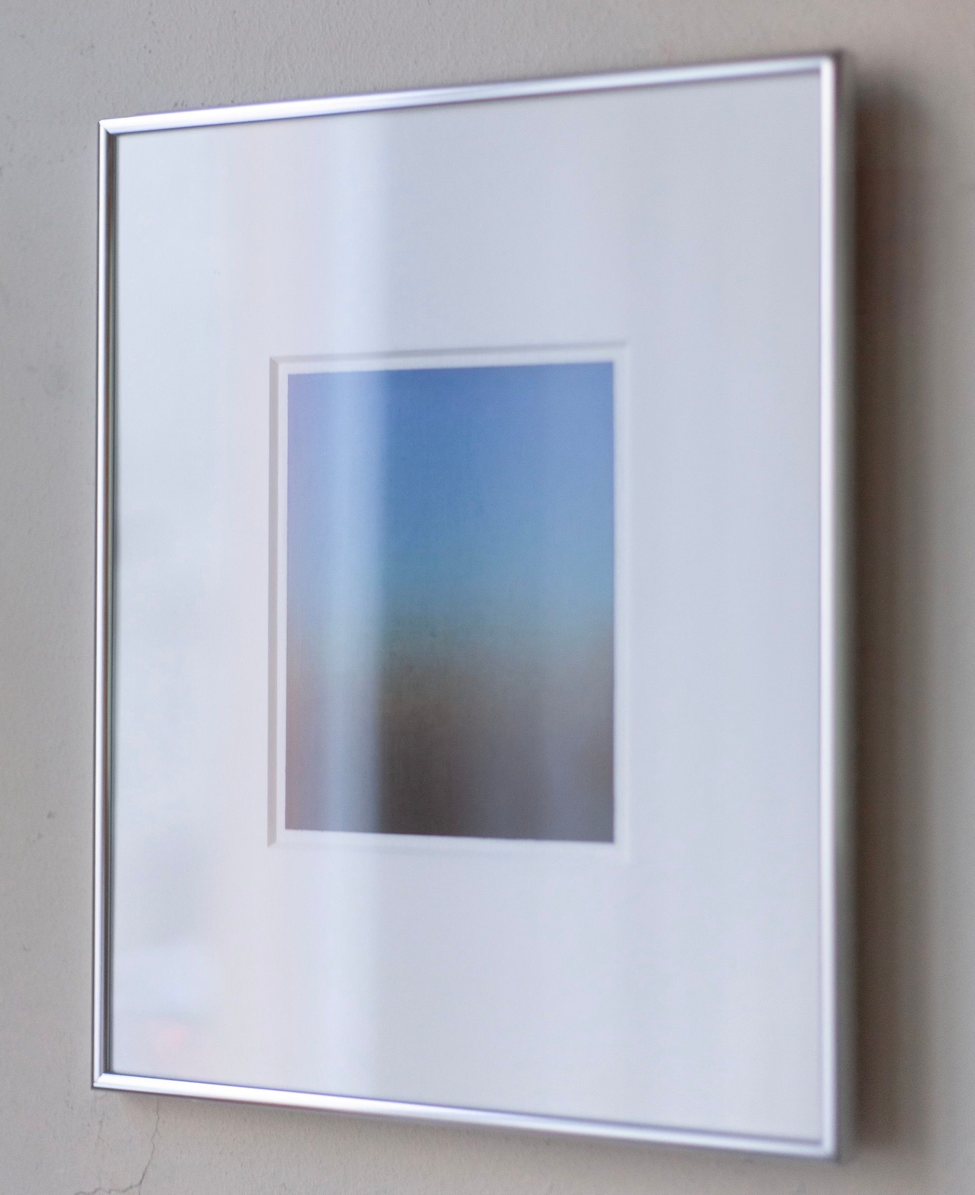 The 'Untitled' Painting, 2024 by Rebecca von Matérn, a minimalist piece with a gradient of blue and earthy tones, is signed by the artist and hung on a light gray wall. Its slim aluminium frame enhances its aesthetic perfectly.