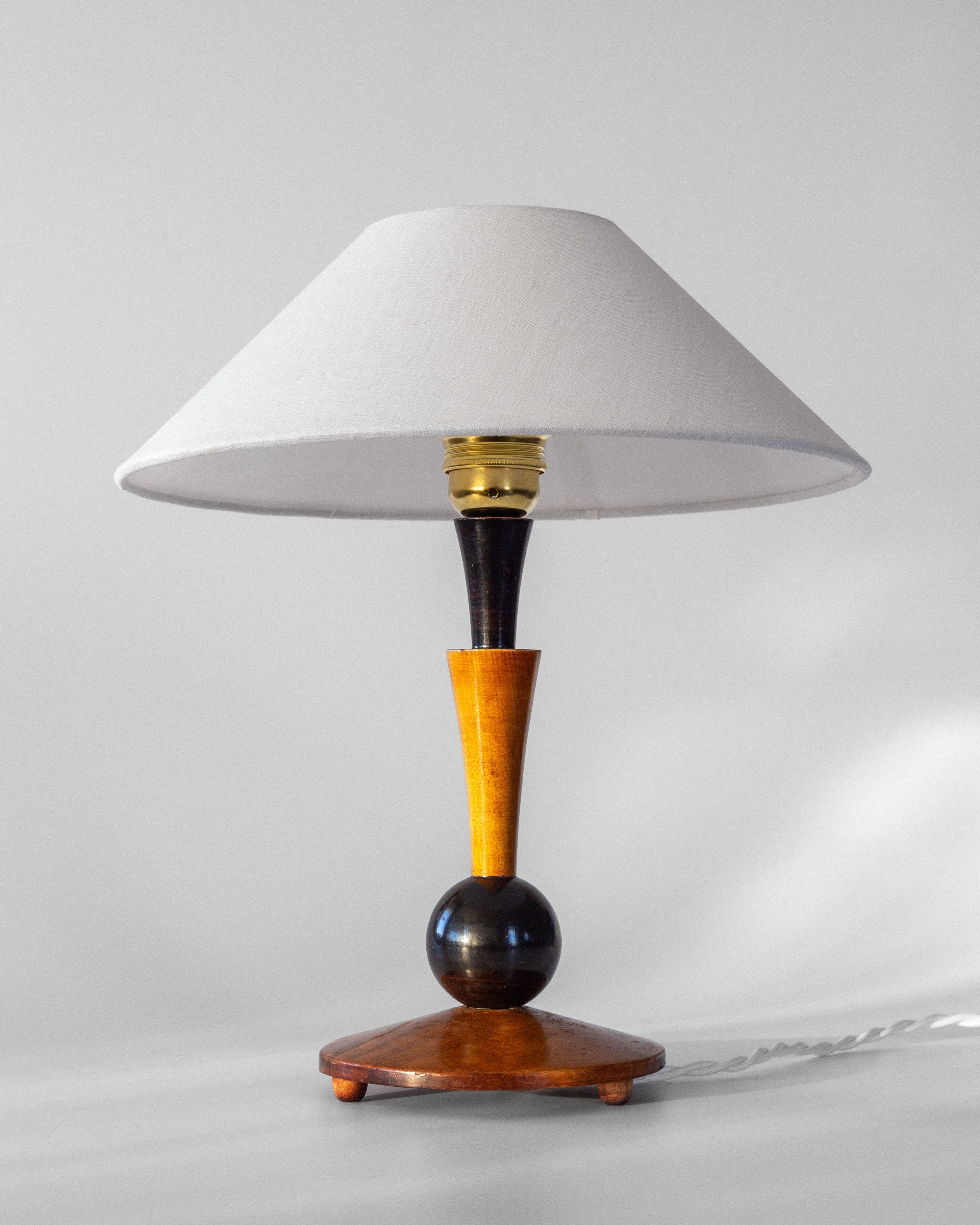 Introducing the Art Deco Wooden Table Lamp by Spigel, a stylish piece featuring a white conical shade and a wooden base with a distinctive spherical black and yellow design. This 1935 handmade creation, set against a light gray background, beautifully exudes vintage character.