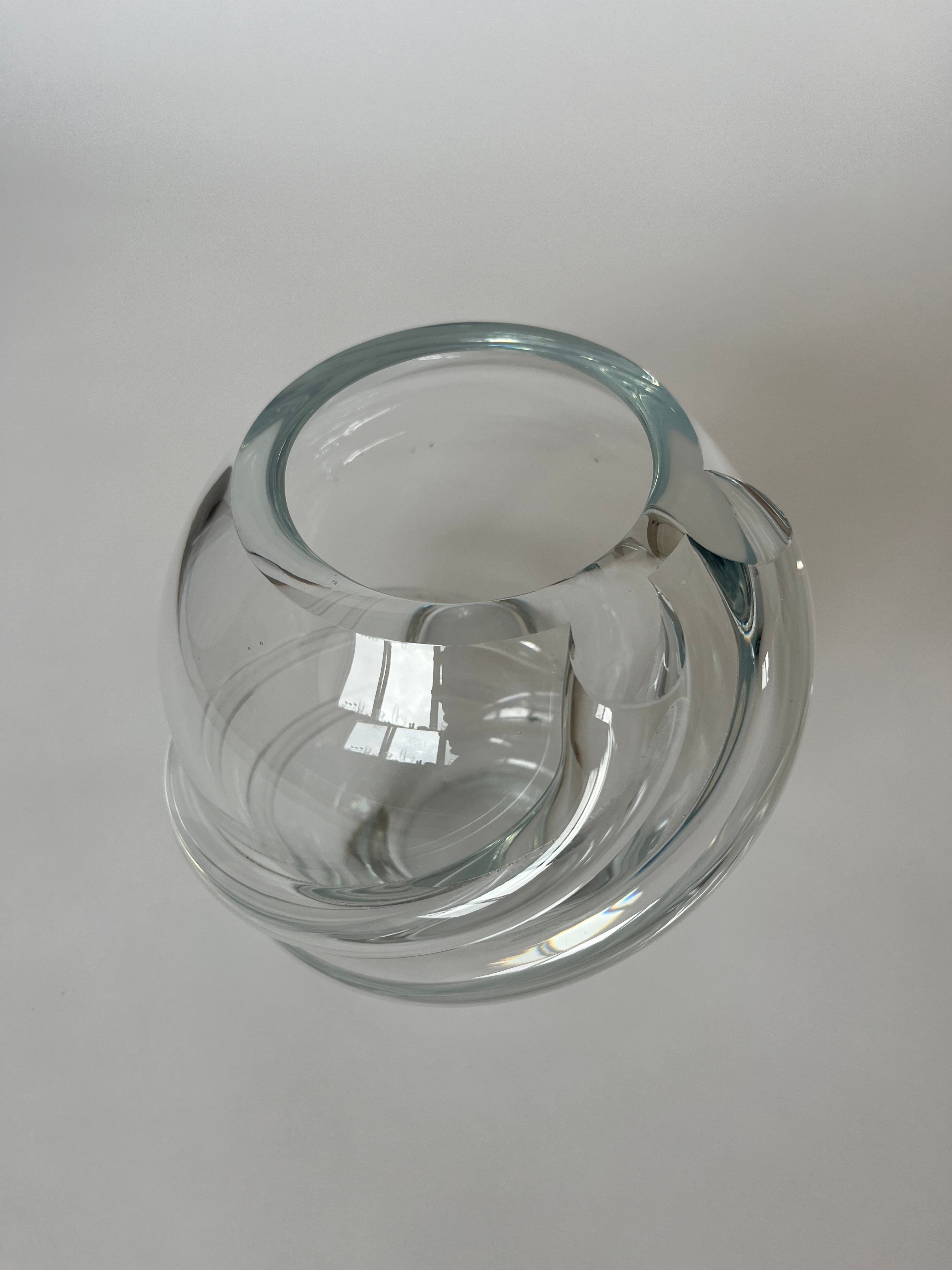 Against a plain white background, the Vintage Crystal Vase by septembre studios captivates with its round glass form enhanced by an intricate swirl detail and layered design. This exquisite piece, echoing the craftsmanship reminiscent of Royal Leerdam, features a smooth surface that elegantly reflects light to create bright highlights.