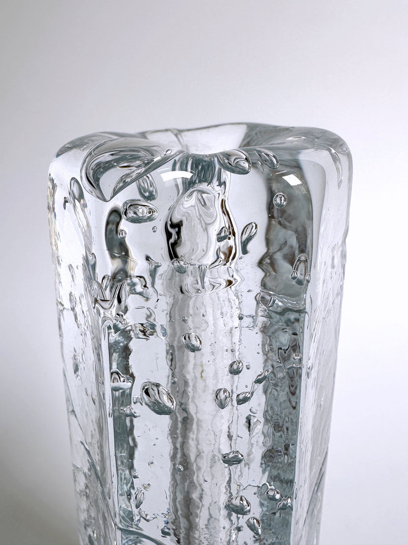 A close-up photograph of the 70s Swedish glass vase by Dodo Vintage, showcasing small air bubbles trapped within its thick glass walls. The Ice glass technique adds texture and visual interest to this vintage piece, set against a plain white background.