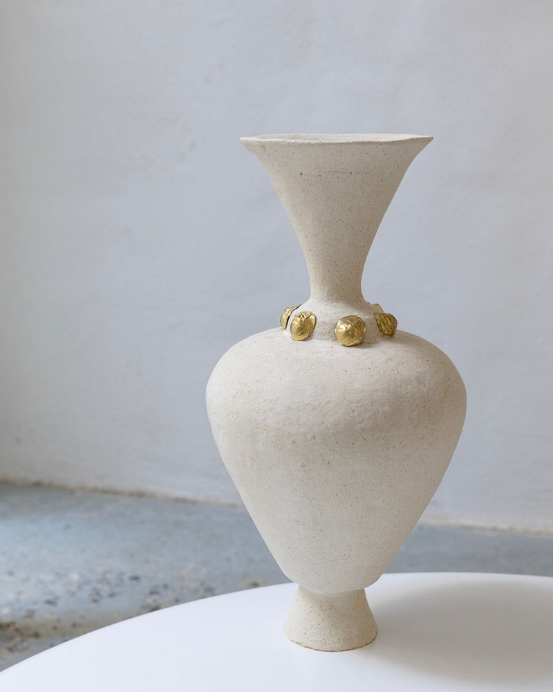 The Isolated n.24 Vase by Canoa Lab—a beige, textured ceramic piece with a wide flared rim and gold accents around the neck—rests on a white surface against a plain, light-colored background.