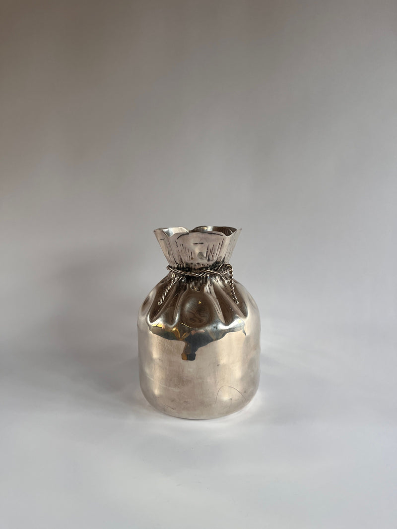 The Silver Plate Vase by Maud Vaughan for Aspreys of London features a rounded base and elegantly crimped, open top like a banker's coin sack. Its vintage silver finish shines beautifully against plain backdrops.