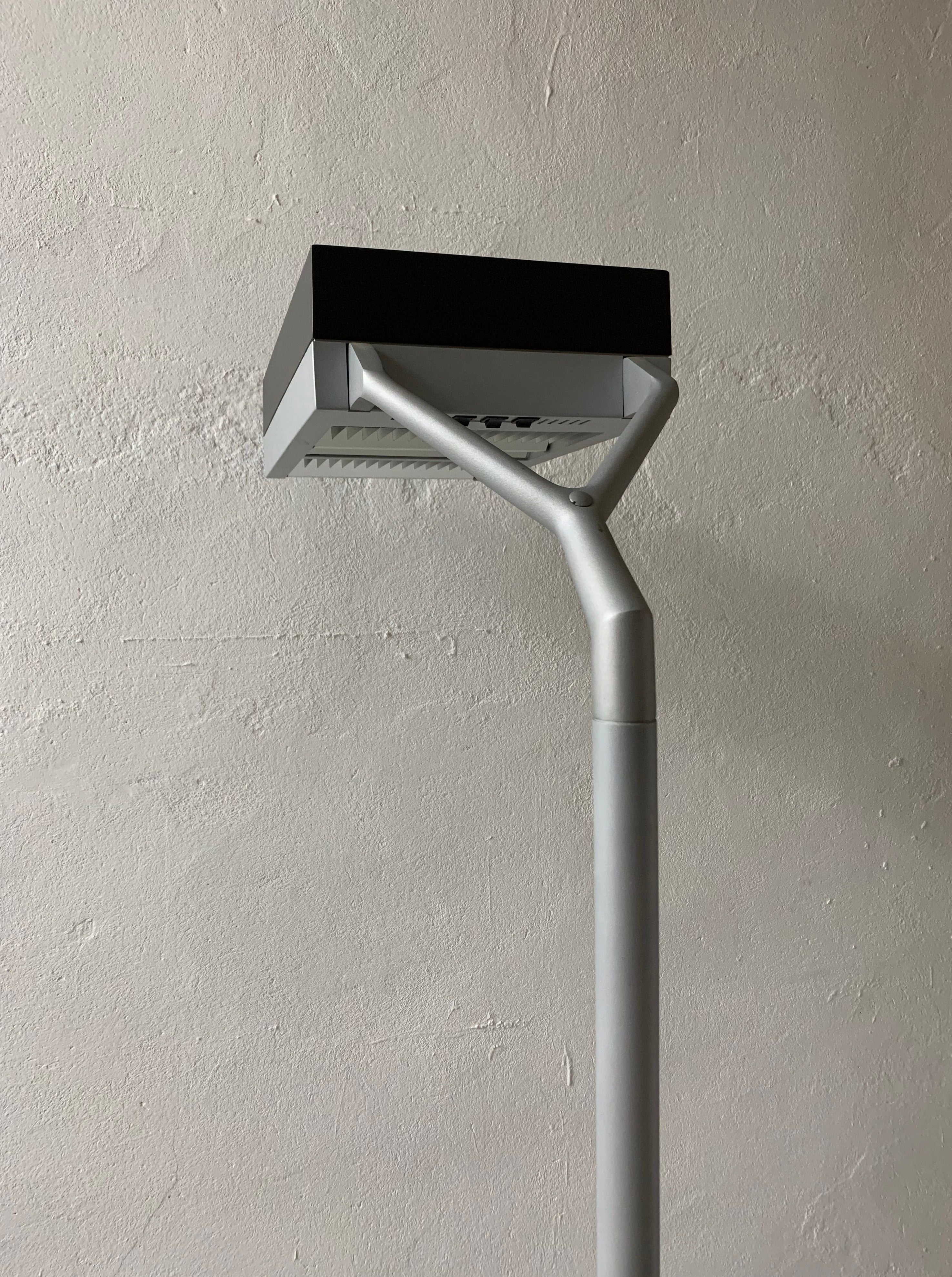 A sleek, modern Veter Vintage LED street lamp with a curved pole and a vintage industrial rectangular lamp head, mounted against a textured gray wall.
