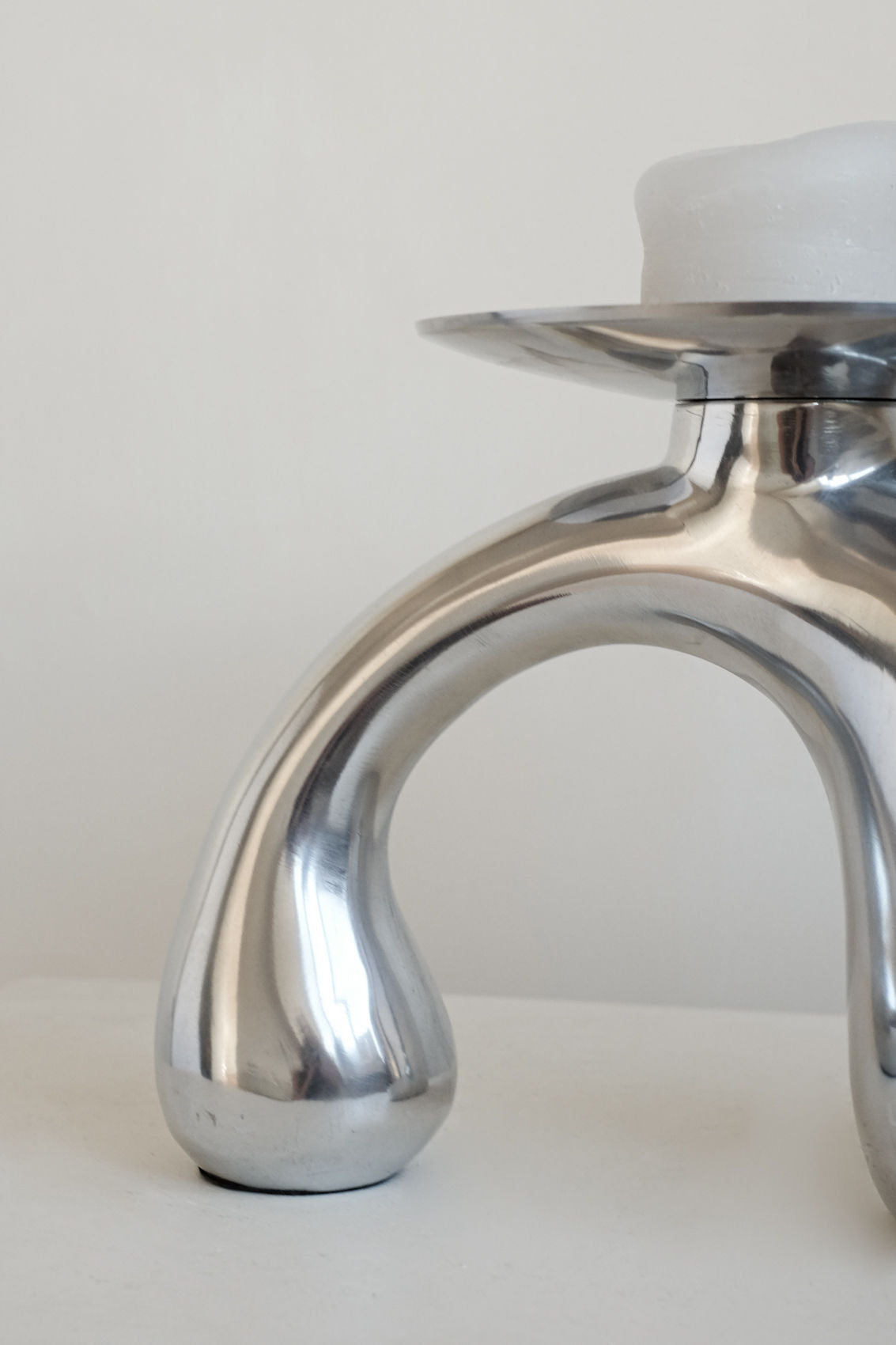The septembre studios Bombastic ‘Drop’ Candle Holder, with its polished metal finish and three curved legs, holds a white candle to add a bold accent to any modern interior.