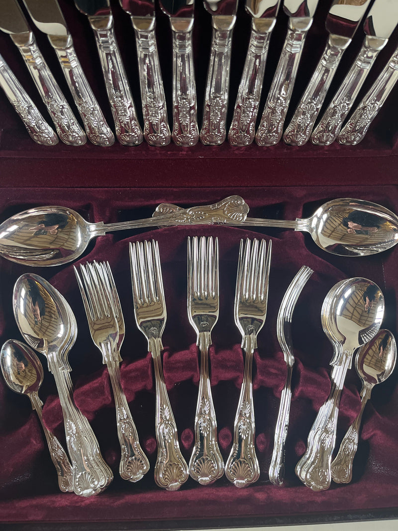 The 44 Piece Boxed Silver Service with Shell Motif by Maud Vaughan displays a collection of silver plate flatware in a maroon velvet-lined case, featuring intricately designed spoons, forks, and knives.