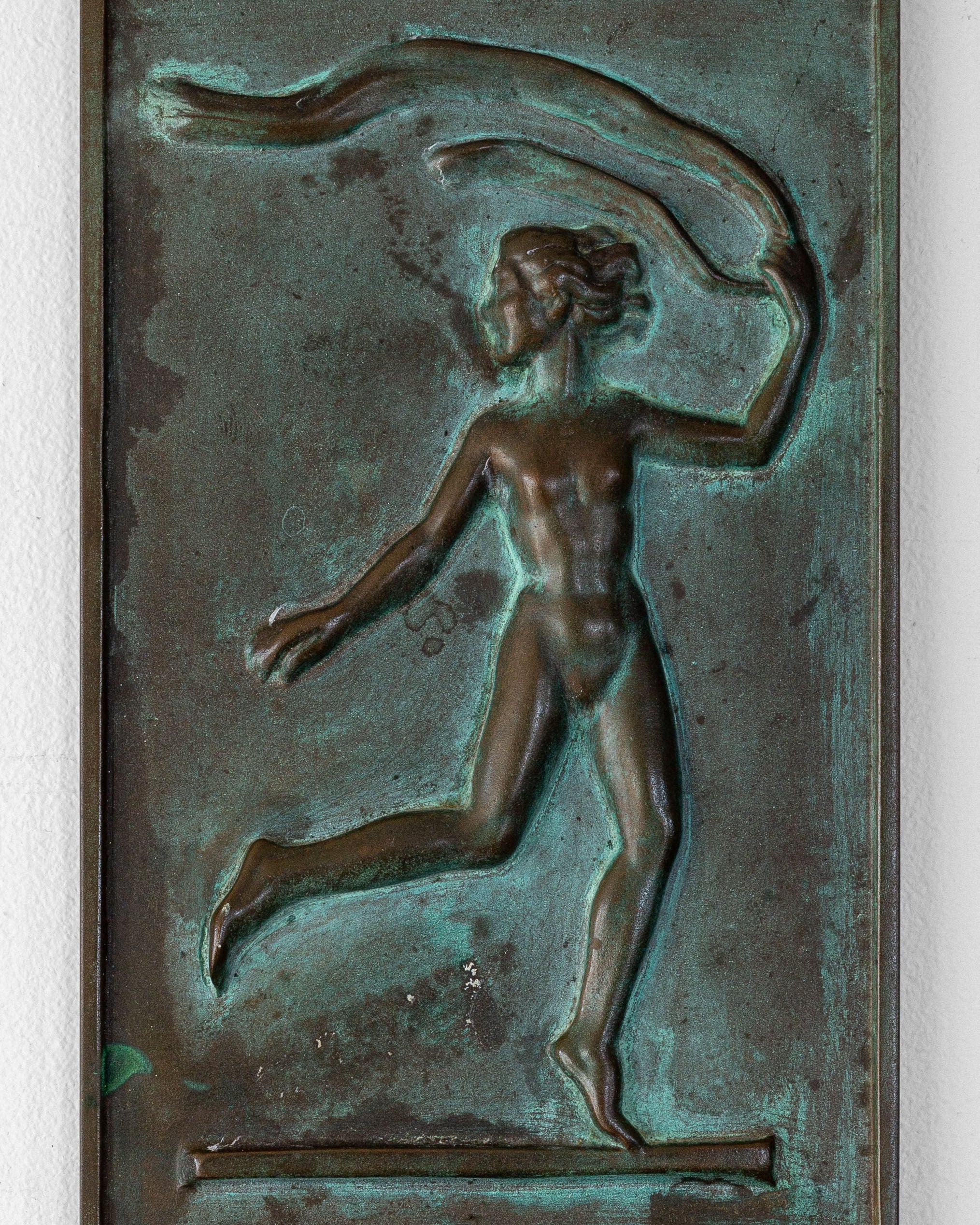 The Bronze Wall Relief by David Jahrl for Spigel features a dynamic figure in motion with a ribbon-like object overhead, set against a textured backdrop, capturing the essence of Swedish Grace style with its green patinated bronze finish.