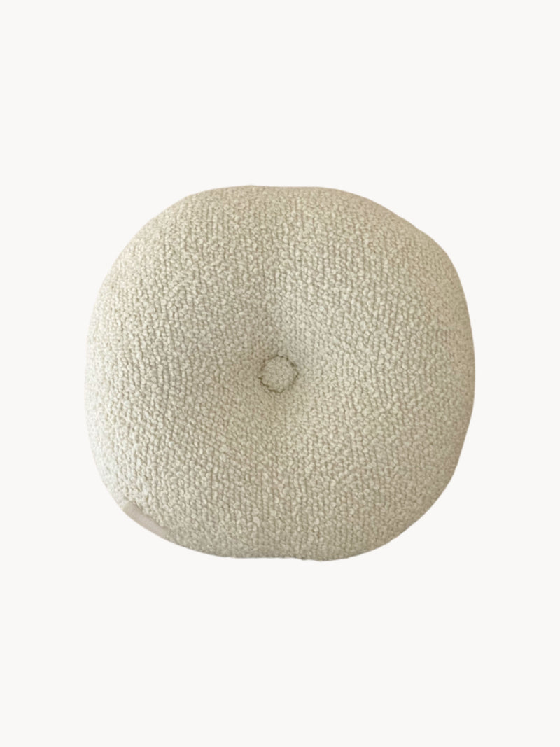 A round, cream-colored handmade cushion with a central button. The cushion boasts a textured wool bouclé fabric made from British eco wool, and appears plush and comfortable. The background is white.

Product: Le Rond - Moyen - Wool Bouclé - Egg White by AMÉLIORÉ