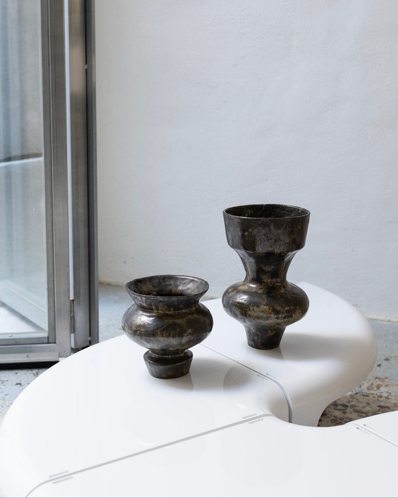 Two dark obsidian ceramic vases on white surface, lifestyle view
