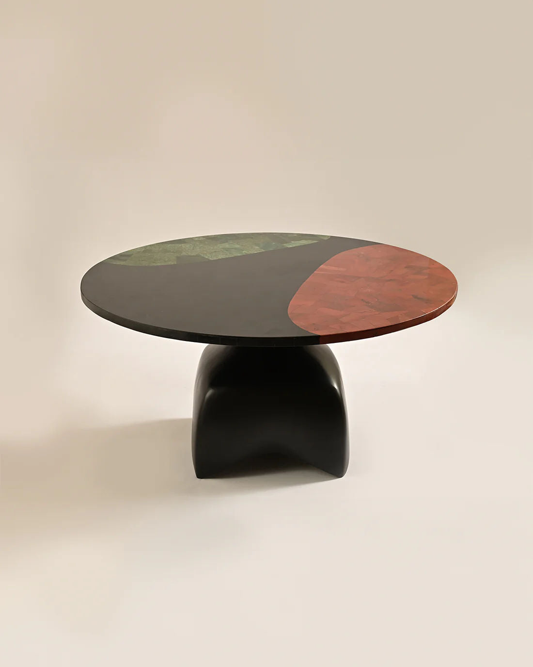 The LMNOH Jasper Coffee Table features a dark, two-tone top with green and reddish-brown stone-like segments. Its base is an abstract design made from cast aluminum, set gracefully on a light, neutral surface.