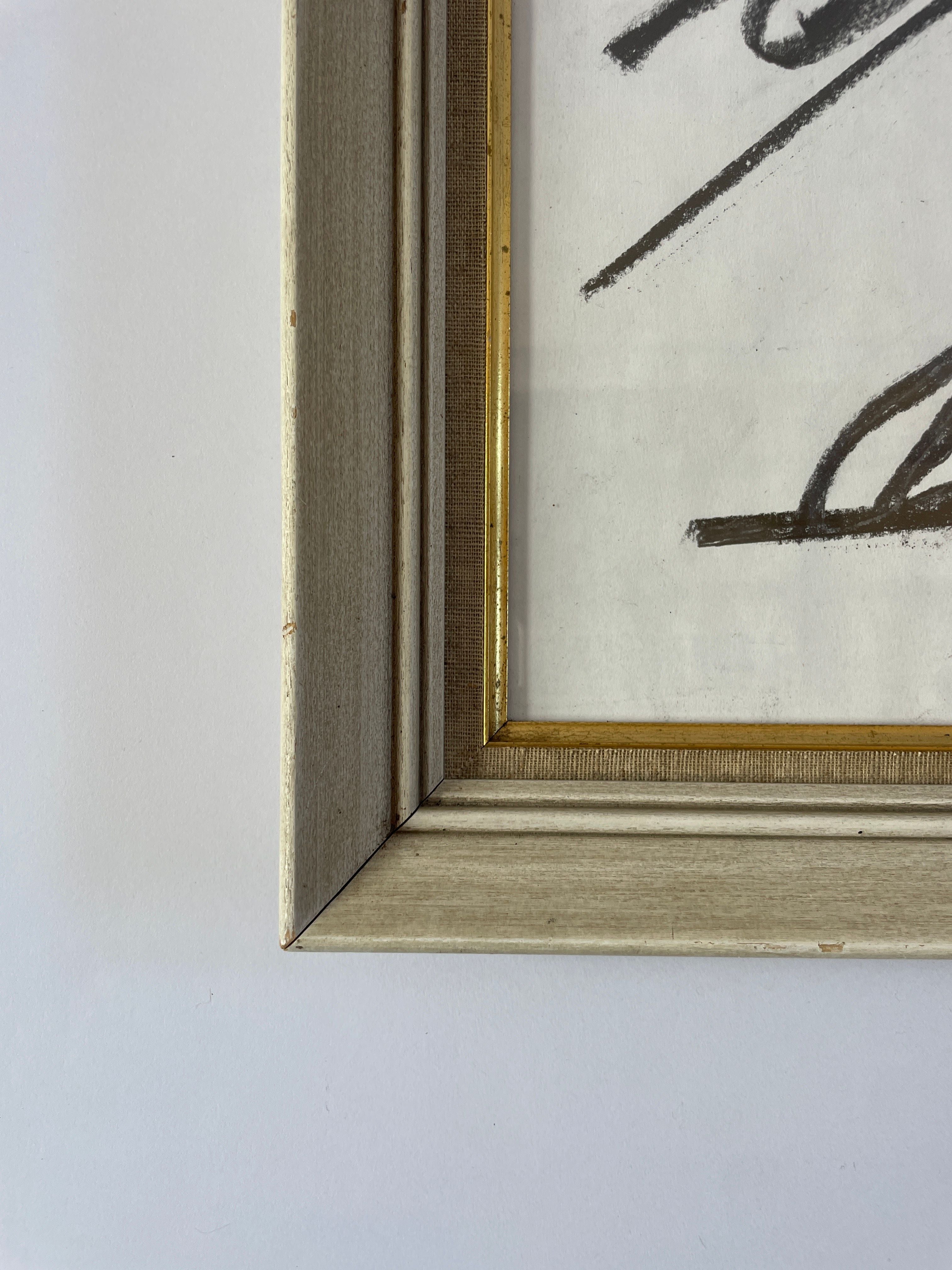 A close-up of the "Nude Artwork by Akop Tashchyan" from Maud Vaughan highlights its beige and gold frame, showcasing the wood texture against a white background. The piece features black brushstrokes that reflect the mixed media abstract style for which LA artist Akop Tashchyan is known.