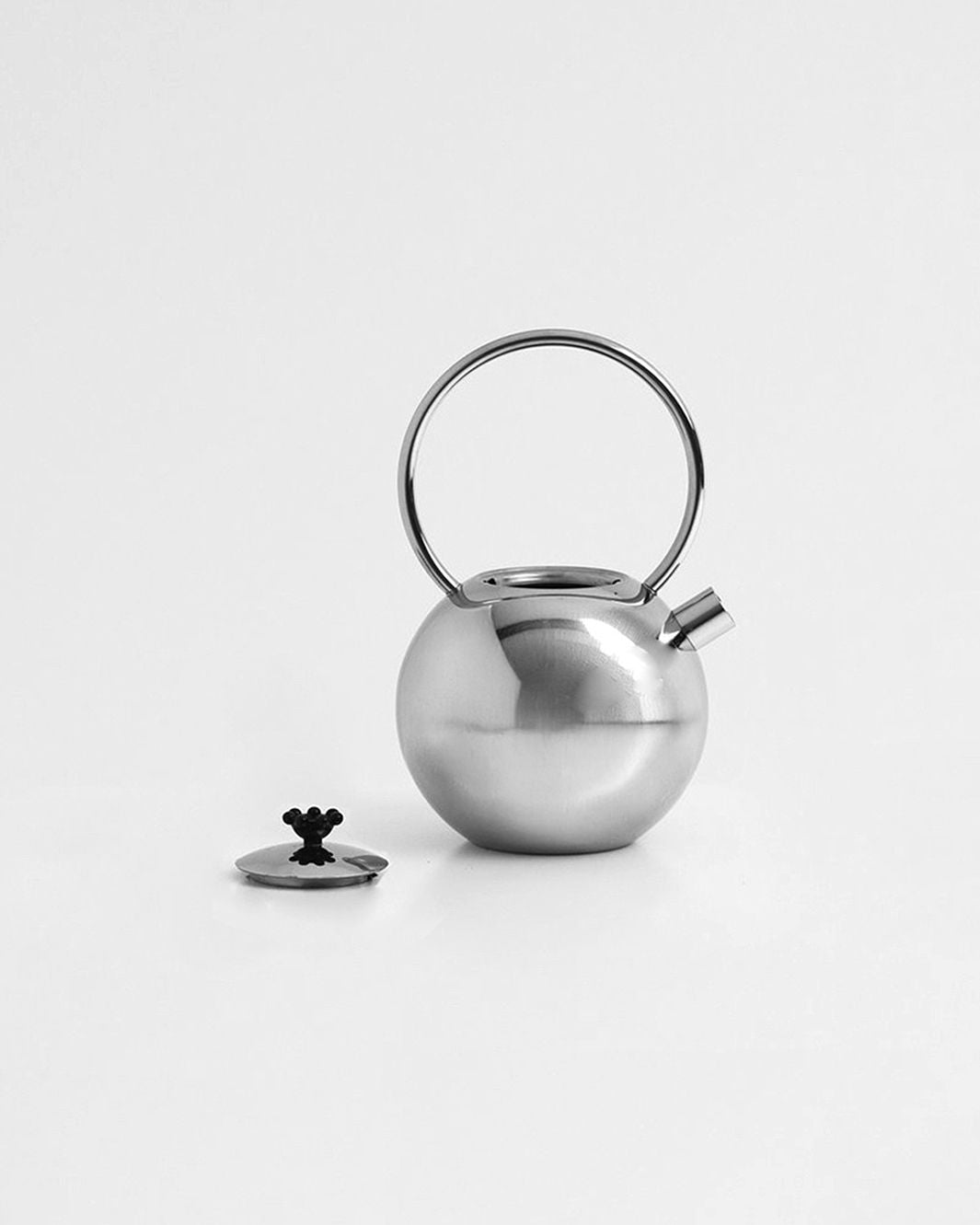 A sleek, modern Chrome teapot by Matteo Thun for WMF, available from Dodo Vintage, features a spherical body and a handle that extends upwards in a circular shape. The lid, adorned with an ornamental black knob, is placed next to the teapot on a white background.