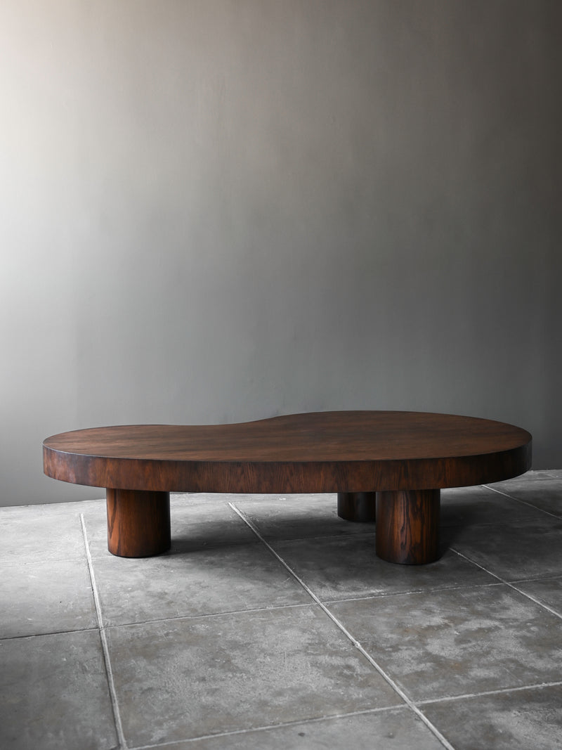 Norman stained oak coffee table with cylindrical legs on concrete floor
