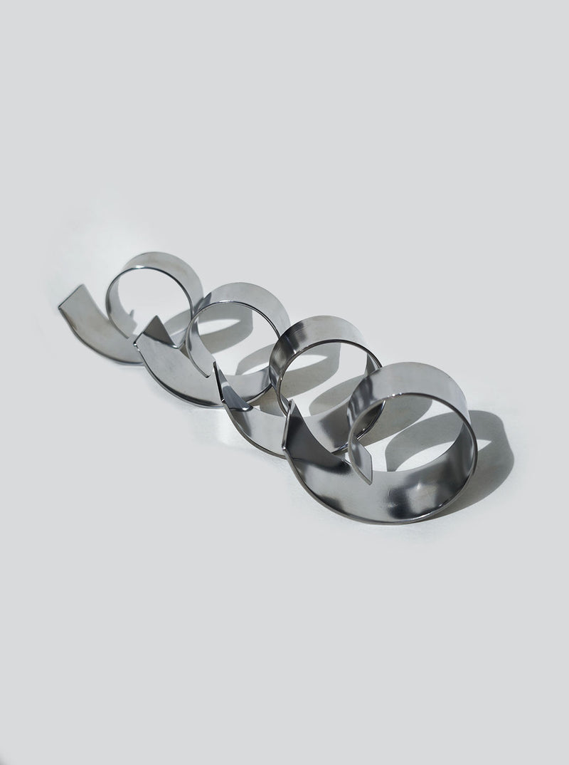 Metallic spiral napkin rings arranged in curved line showing reflective surface