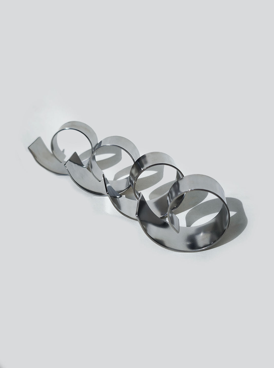 Metallic spiral napkin rings arranged in curved line showing reflective surface