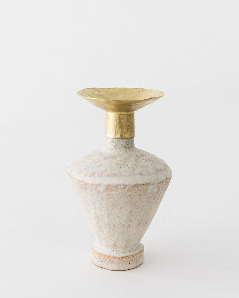 The Isolated n.6 Vase by Canoa Lab features a wide, textured ceramic base and a flared gold-toned metal rim, inspired by Mediterranean ceramics, and is shown against a plain white background.