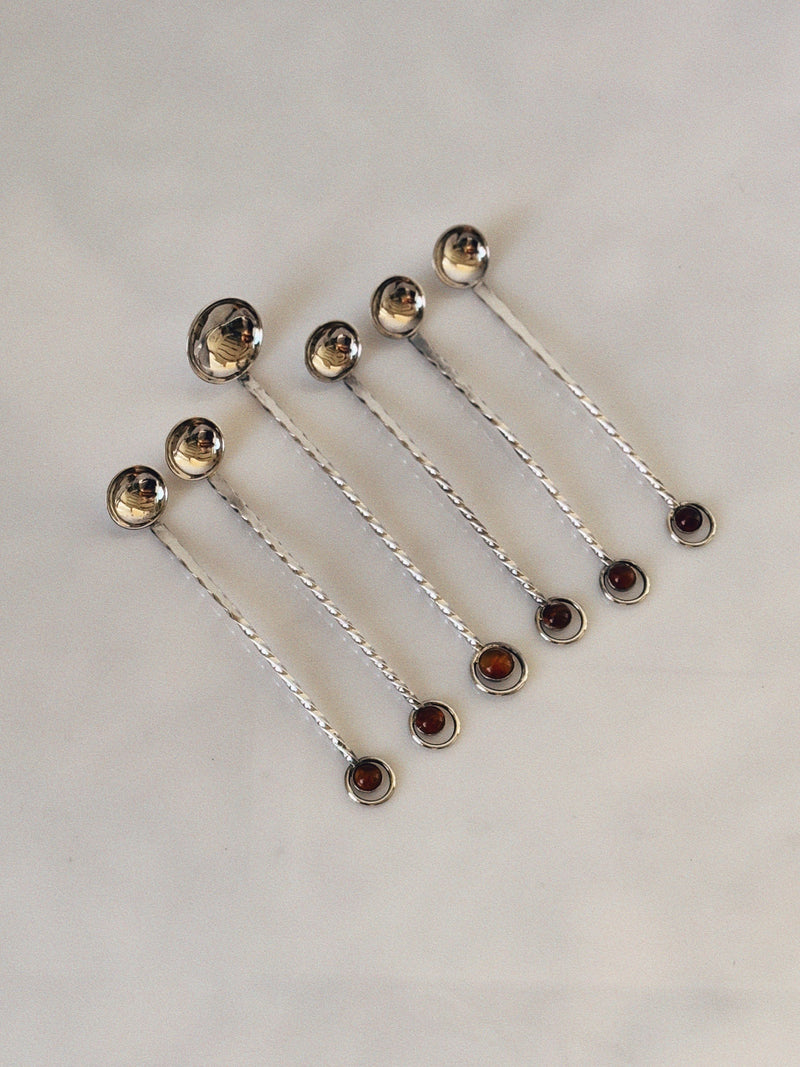 Six silver-plated spoons with amber crystal handles arranged diagonally