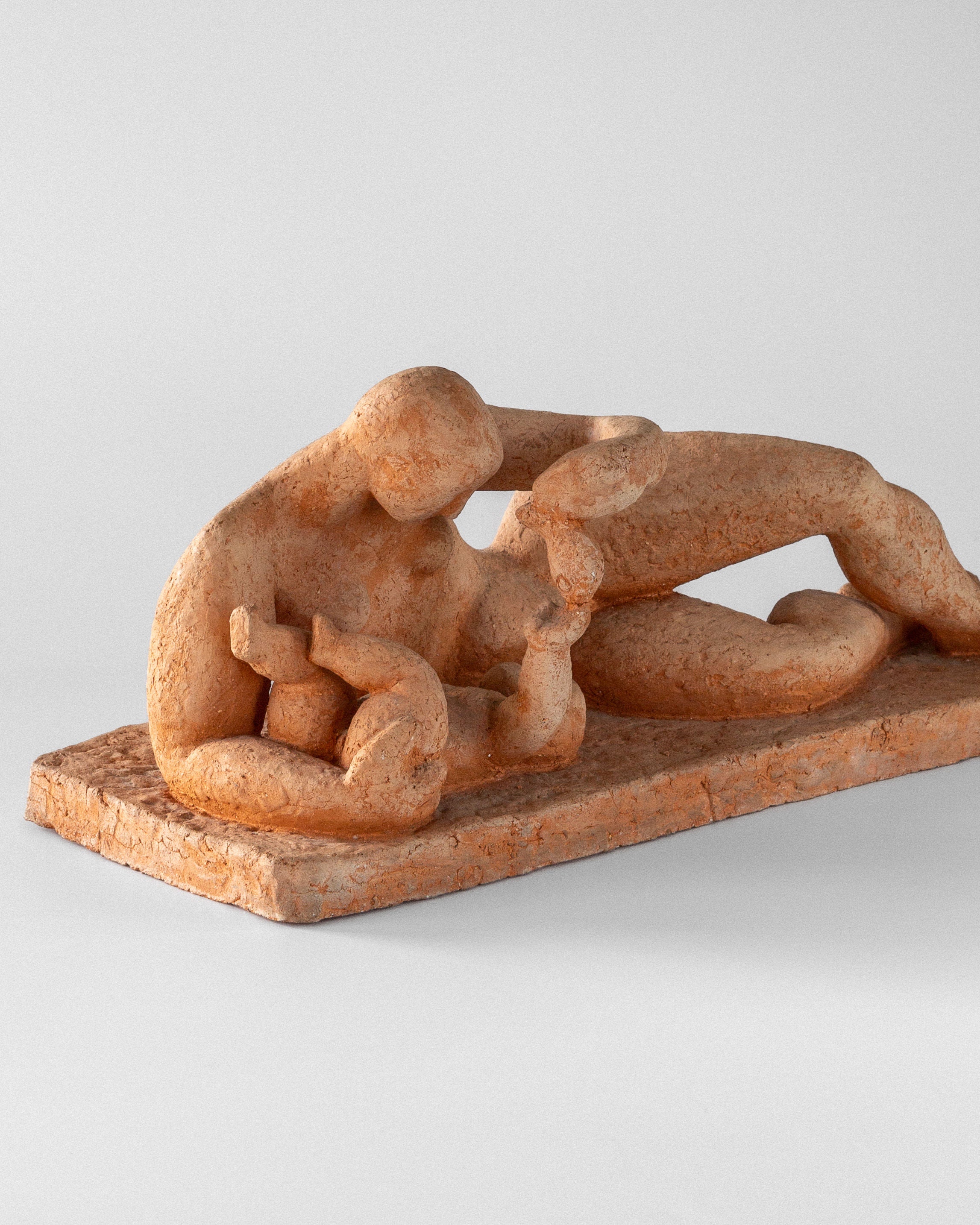 A Swedish modernist piece by Spigel, the Modernist Terracotta Sculpture by Bengt Amundin from the 1950s showcases a reclining figure with an outstretched arm in earthy tones. Crafted in unglazed terracotta and resting on an elongated rectangular base, it embodies minimalist art against a plain background.