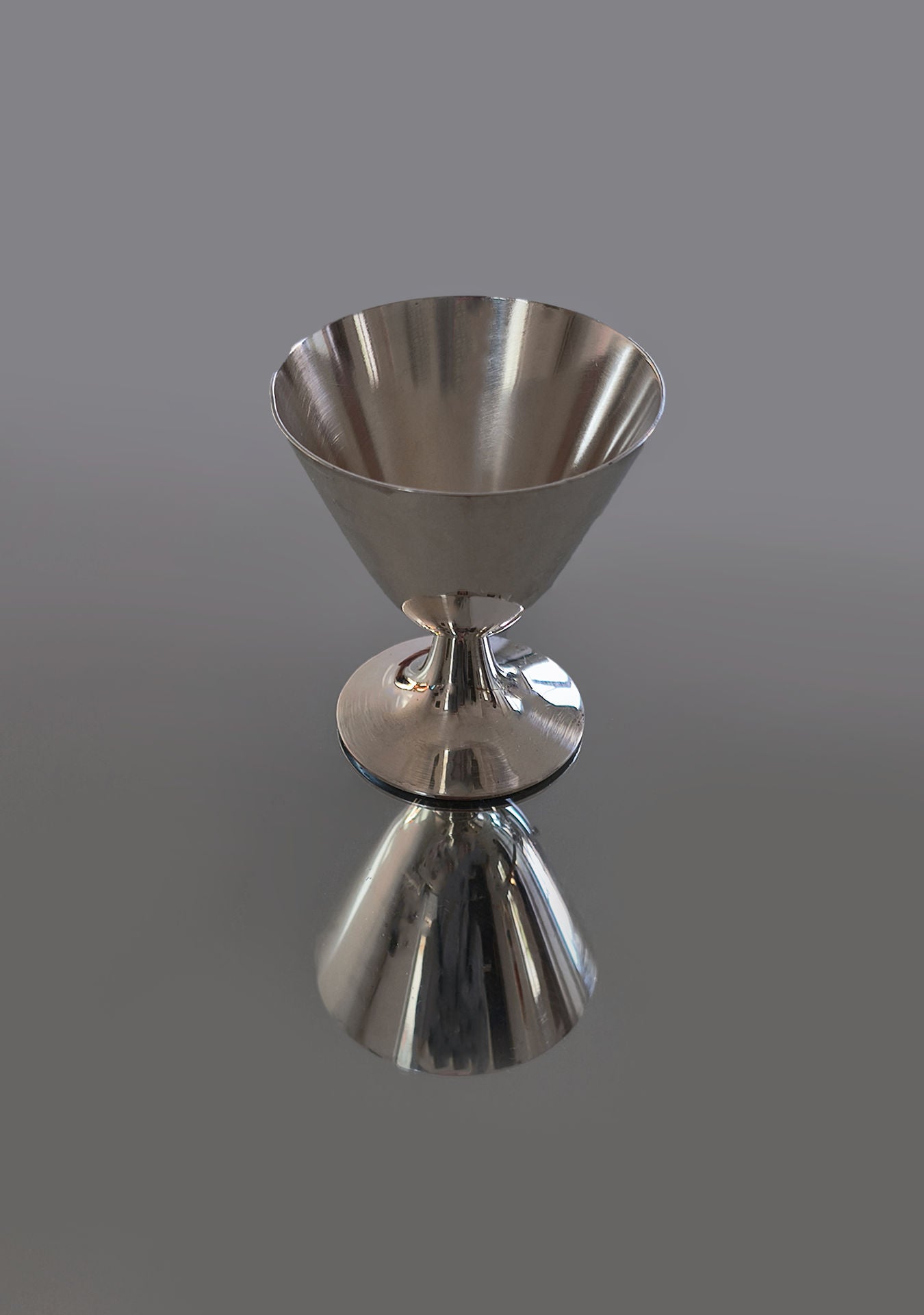 The Set of 6 Christofle Cups by Les Objoies showcases timeless luxury with their shiny silver chalice shape. Against a smooth gray background, they cast clear reflections, embodying the elegance of classic silver-plated cups and are perfect for enhancing home decor.