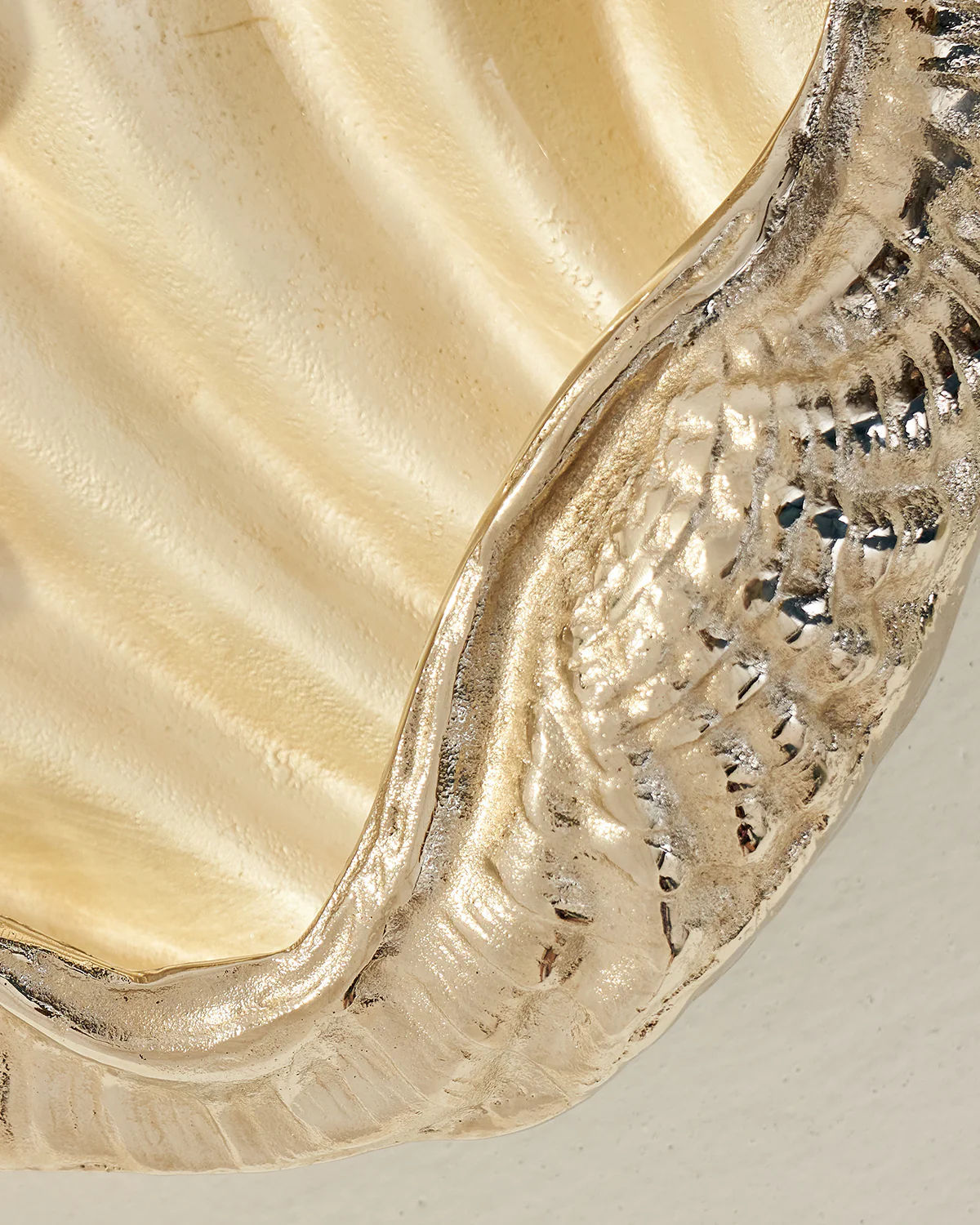 Close-up of an LMNOH Seashell with a shimmering, ridged metallic texture, resembling a decorative object. Its glossy surface reflects light beautifully, making it an ideal wine cooler for chilled drinks against a soft, neutral background.