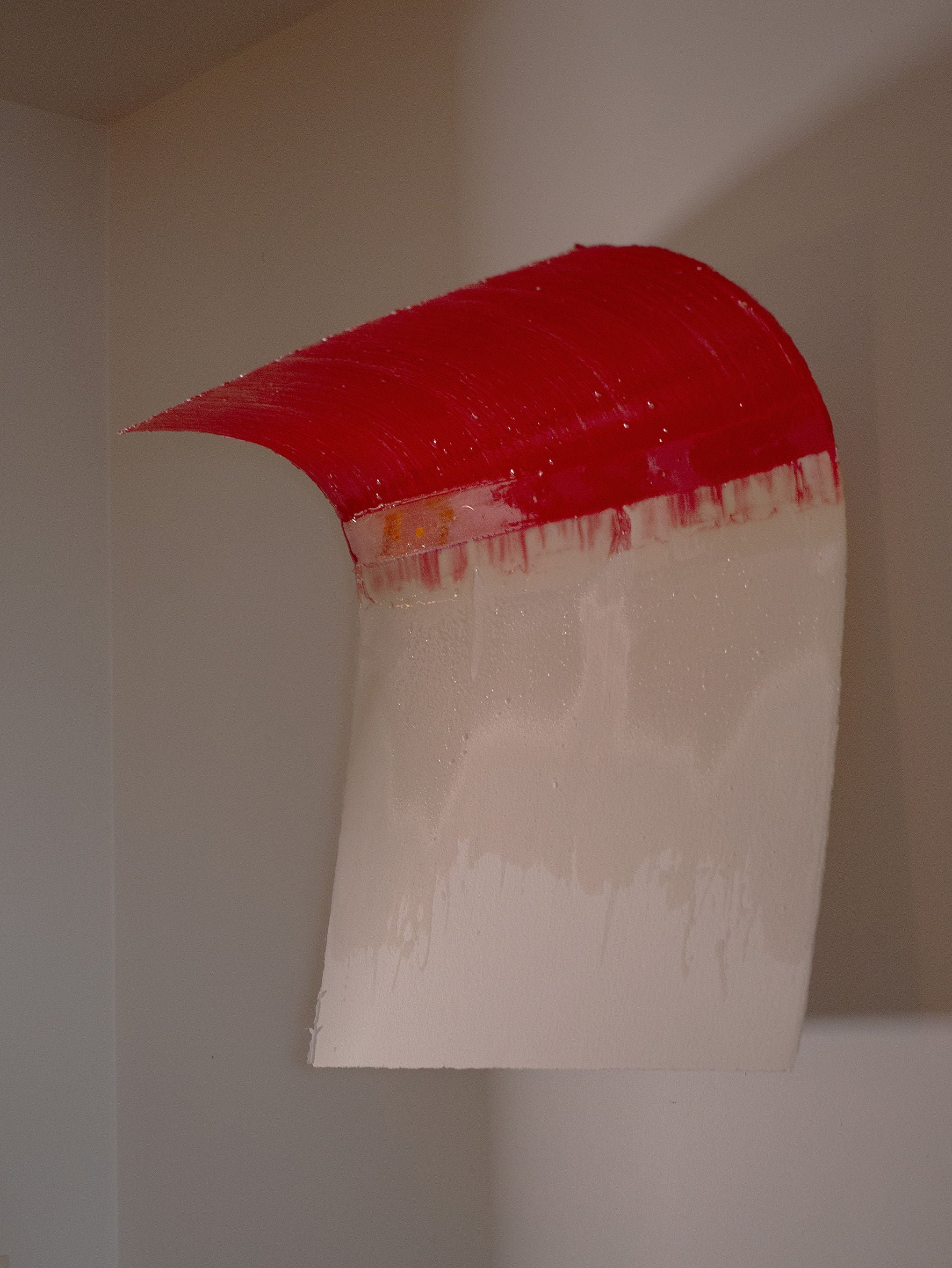 Introducing the "Red Curve" Epoxy Sculpture by STUDIOPOLS, a distinctive minimalist wall art piece. It features a striking curved red top and an off-white bottom, crafted on cold-pressed watercolor paper. The sculpture presents a seamless gradient transition, highlighted with visible brush strokes and subtle texture details, elegantly displayed on a neutral-colored wall.