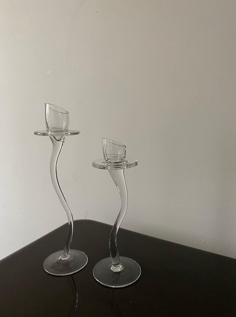 Two Les Objets Amsterdam Vintage Sets of Elegant Candle Holders on a dark wooden surface against a plain light-colored wall.