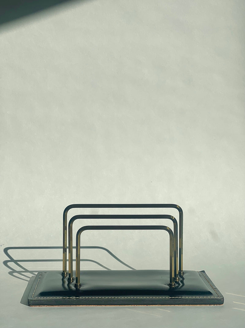 Vintage leather letter holder with brass rails on dark base